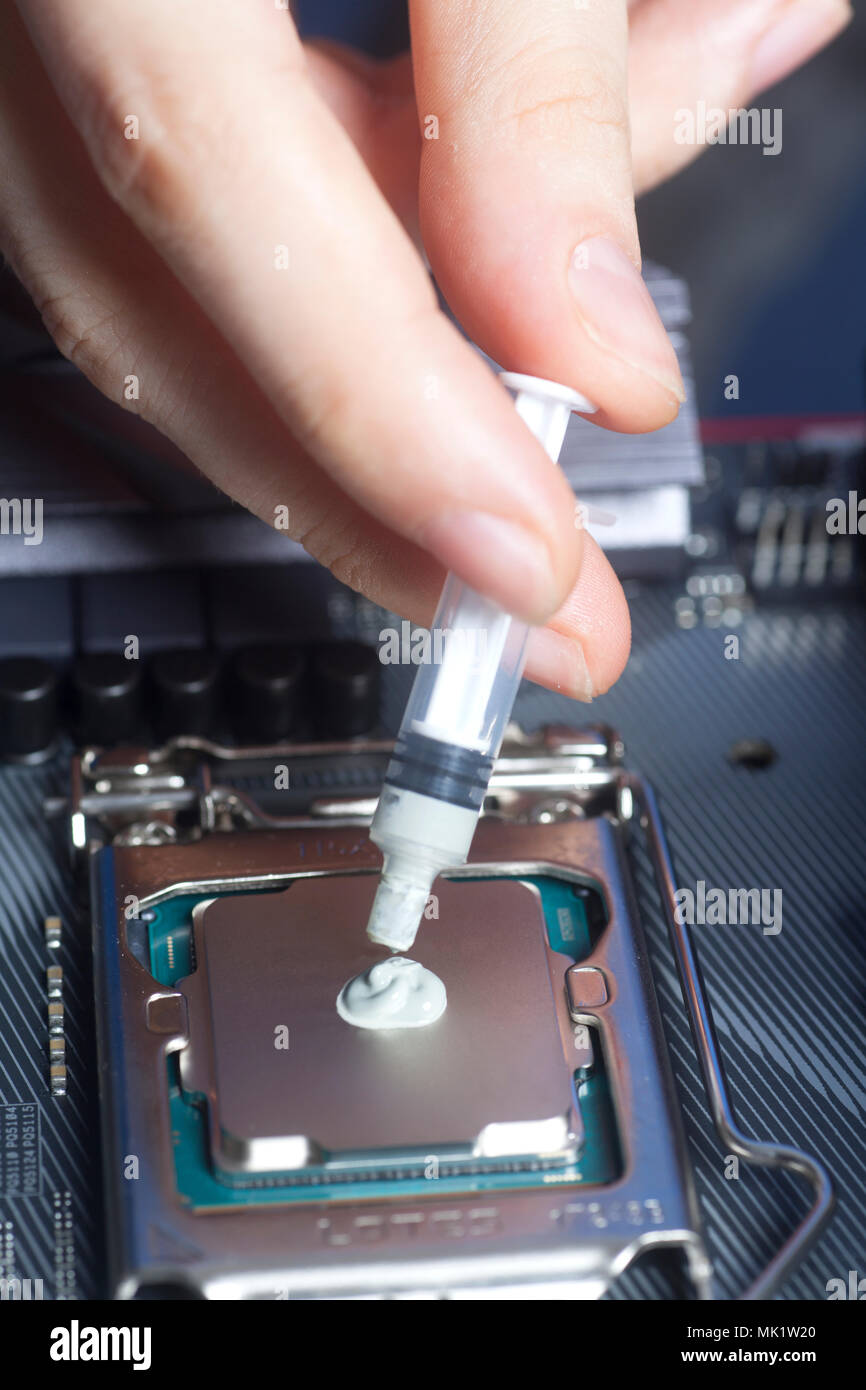 Hand with syringe applying thermal paste on the CPU processor on