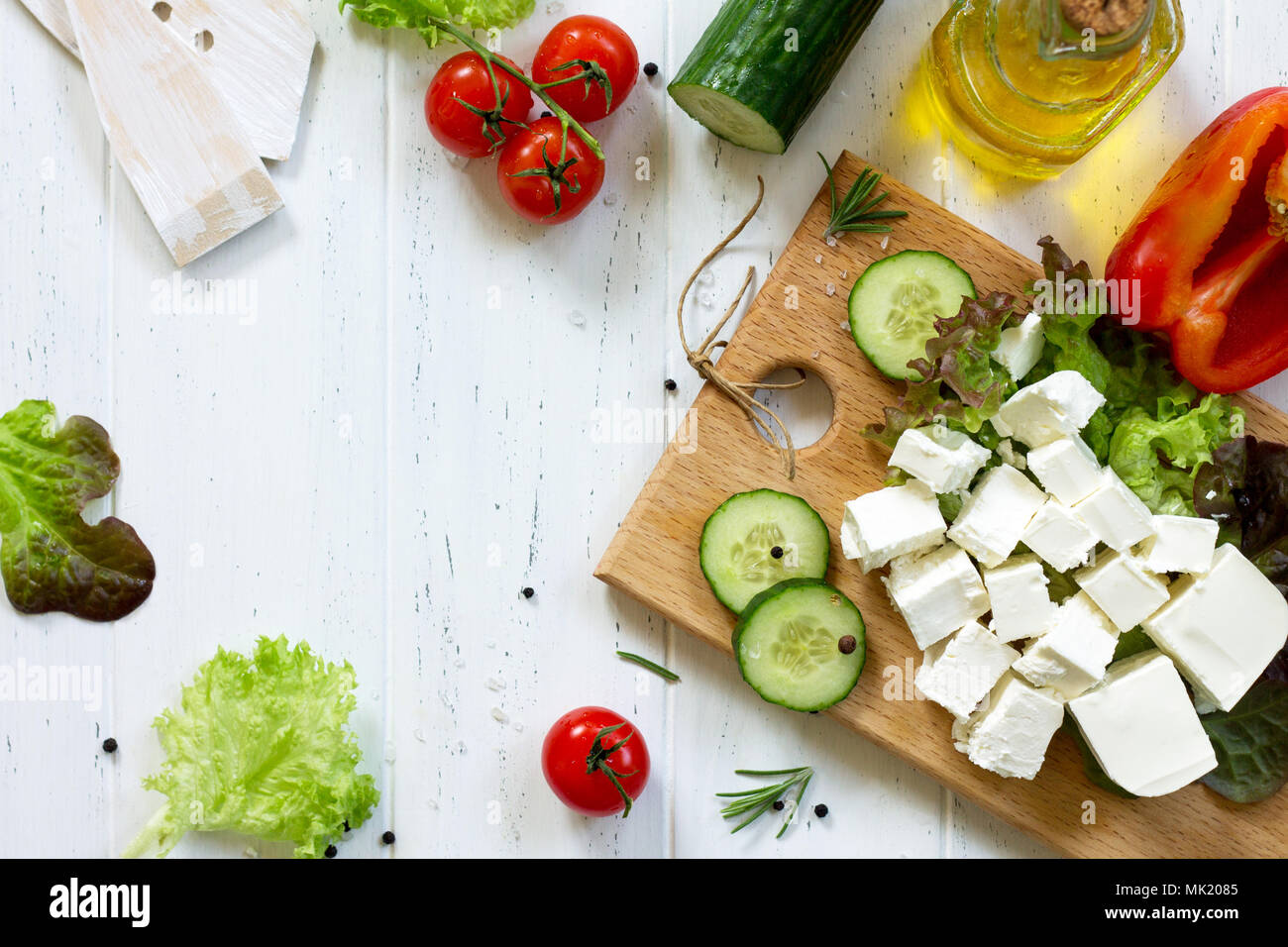 Feta cheese and black olives, cooking qreek salad with fresh vegetables on a white wooden table. Stock Photo