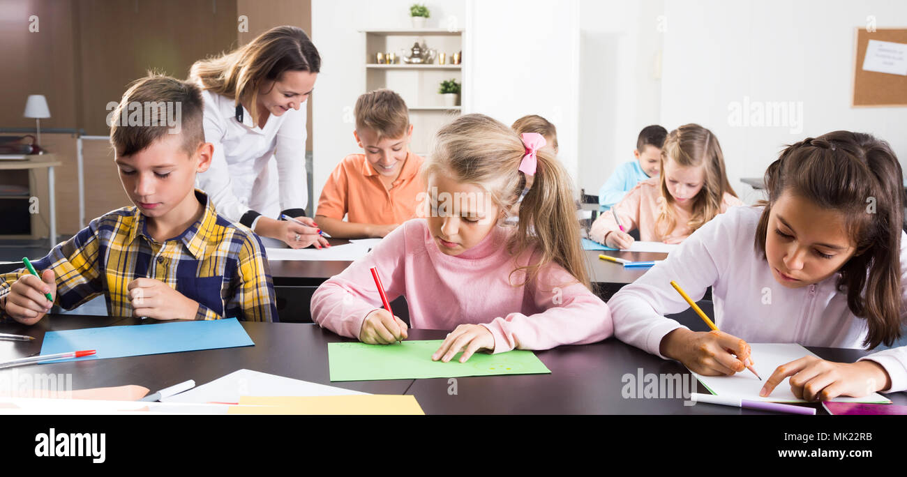 Woman teacher and elementary age kids drawing at class in school Stock ...