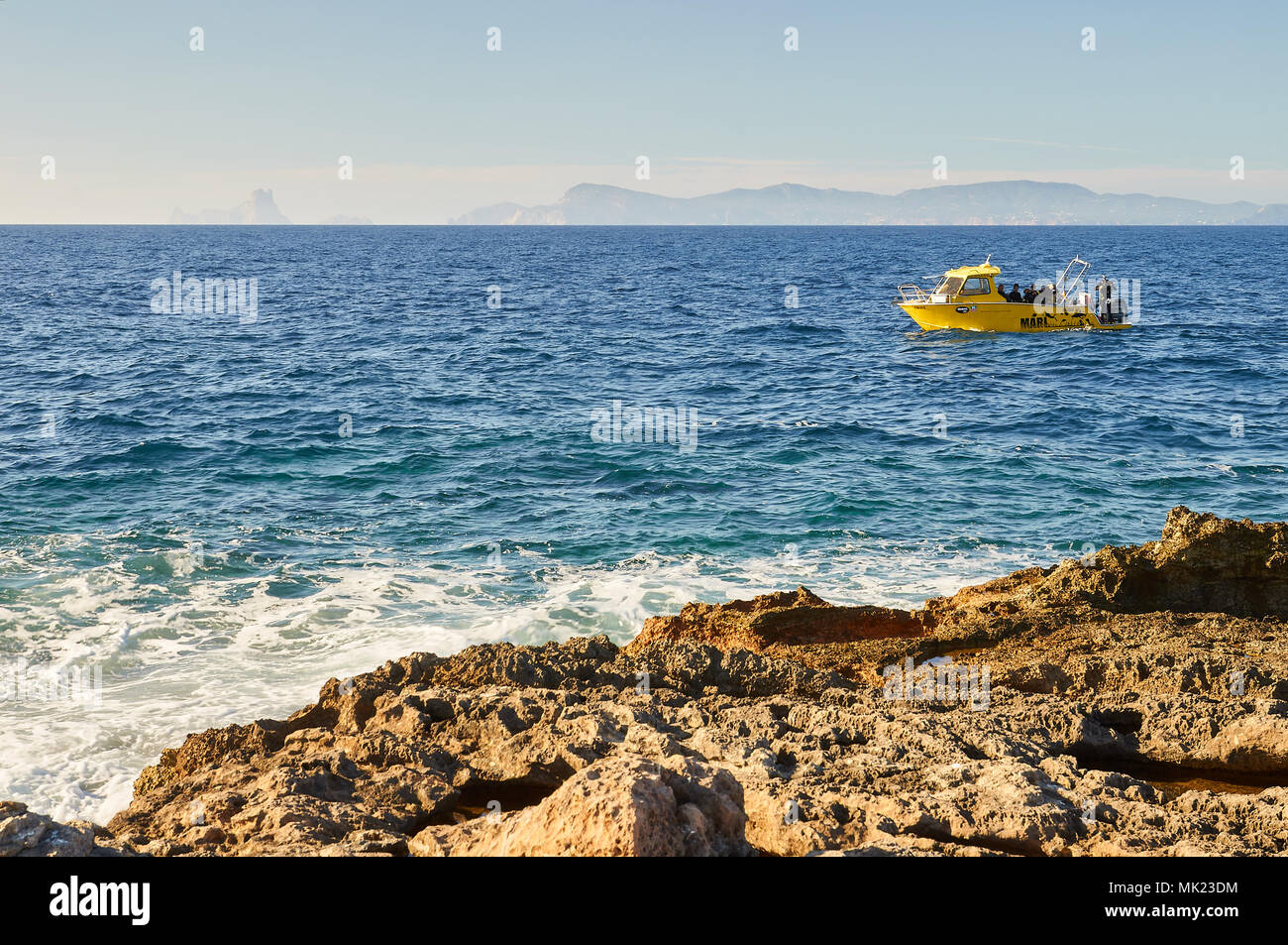 Diving boat with divers near the Punta Gavina coastline with Ibiza and Es Vedrá islands in the distance in Formentera (Balearic Islands, Spain) Stock Photo