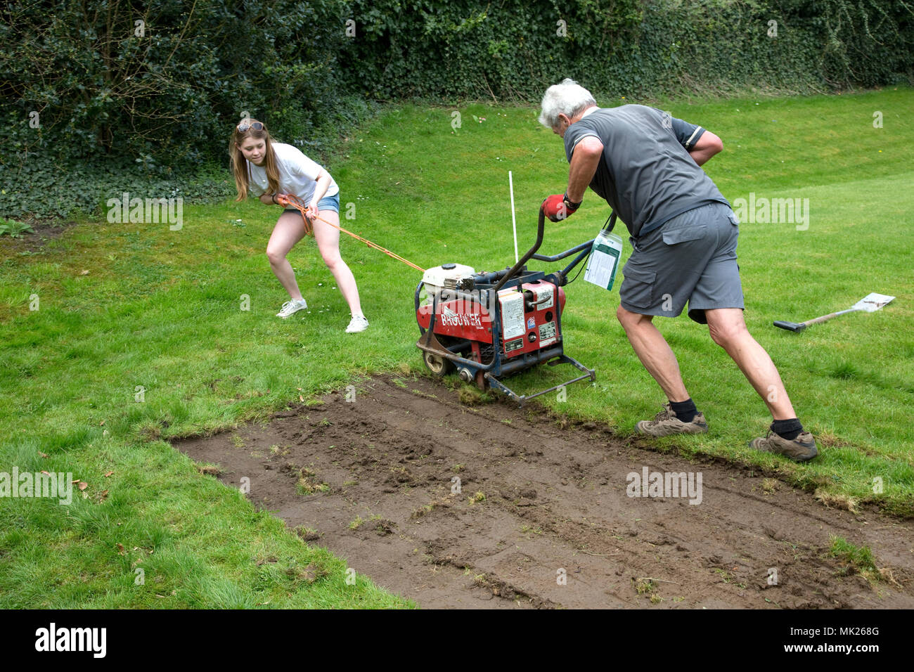 Man and teenage girl turf cutting Three Bees Community Garden April 2018 Mickleton Cotswolds UK Stock Photo