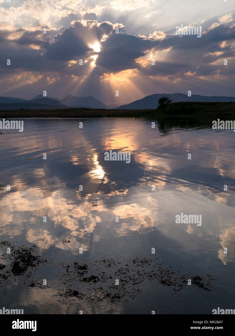 Sunset Sunbeams Radiating Through Cloud And Reflected In Still Waters