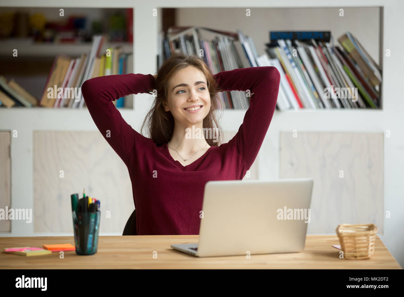 Satisfied female worker leaning in chair after finishing work Stock Photo