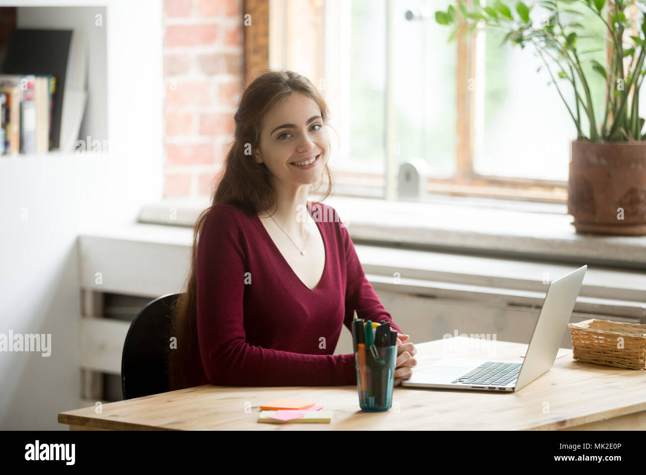 Smiling female posing while working at laptop Stock Photo