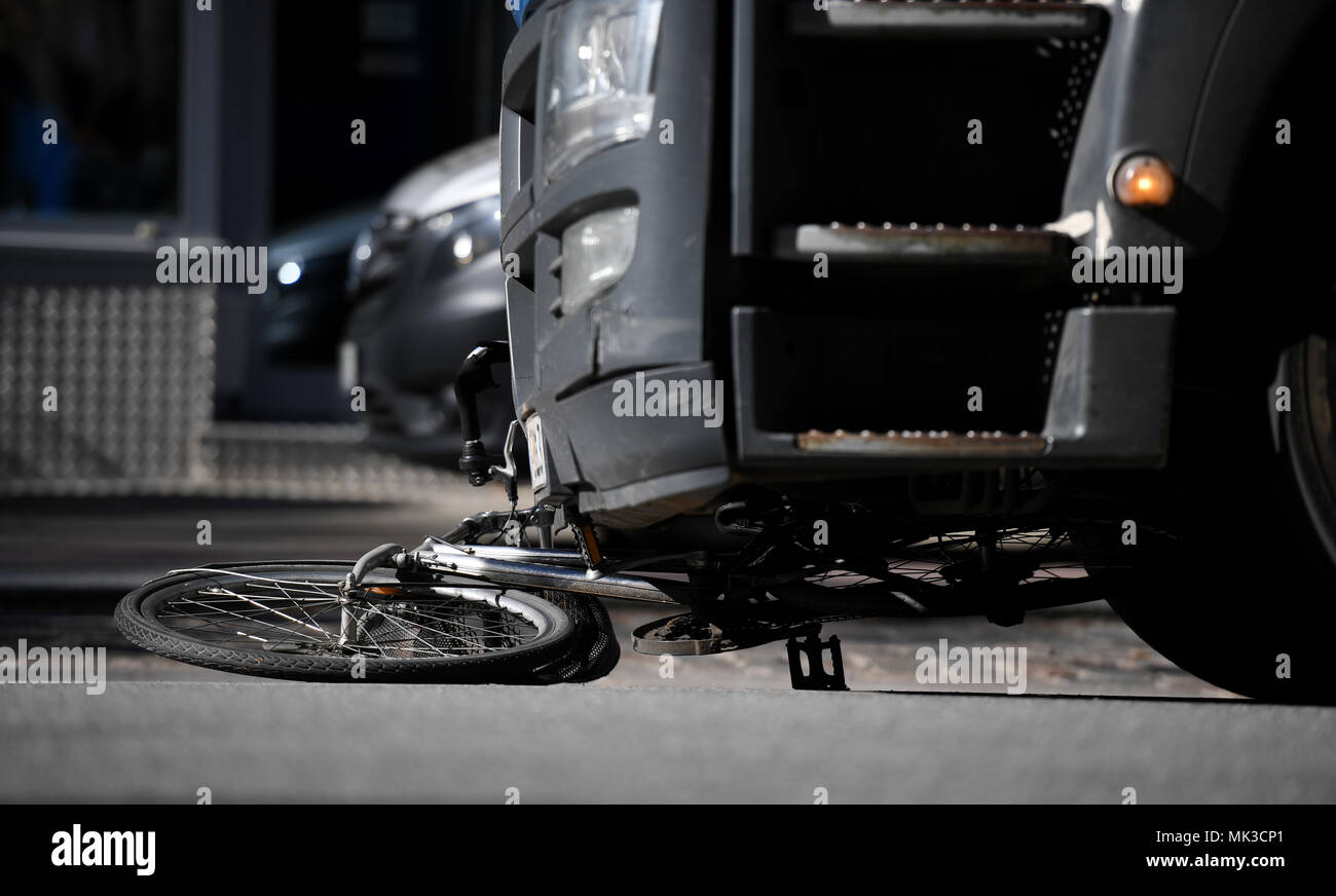 07 May 2018, Germany, Hamburg: A badly damaged bicycle lies underneath a truck. A cyclist lost her life after a collision with a truck in Hamburg-Eimsbuettel on Monday morning. Photo: Daniel Reinhardt/dpa Stock Photo
