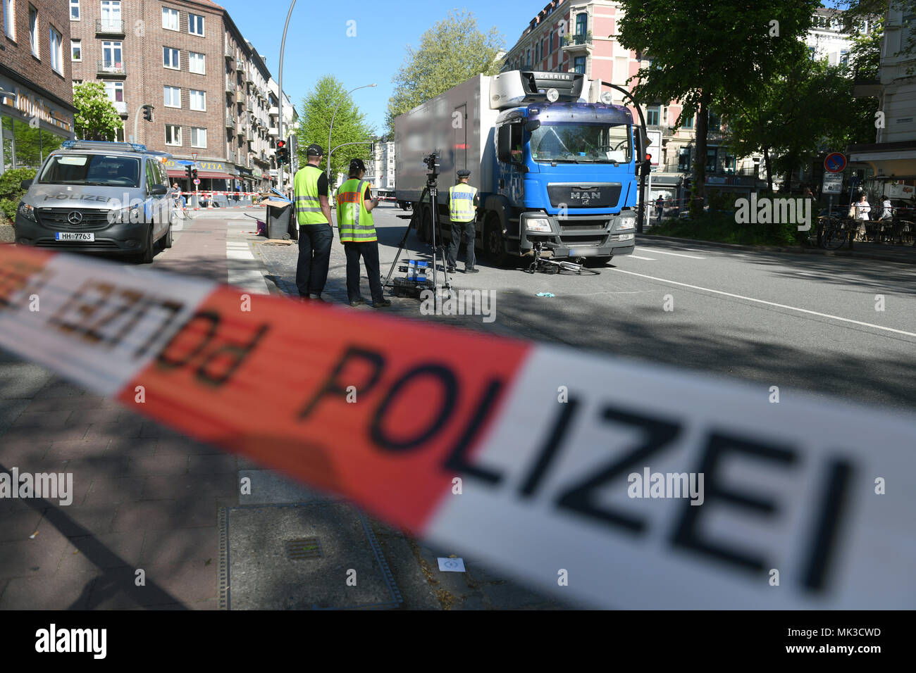 07 May 2018, Germany, Hamburg: A badly damaged bicycle lies underneath a truck. A cyclist lost her life after a collision with a truck in Hamburg-Eimsbuettel on Monday morning. - ATTENTION: parts of the picture were pixelised for legal reasons. Photo: Daniel Reinhardt/dpa Stock Photo