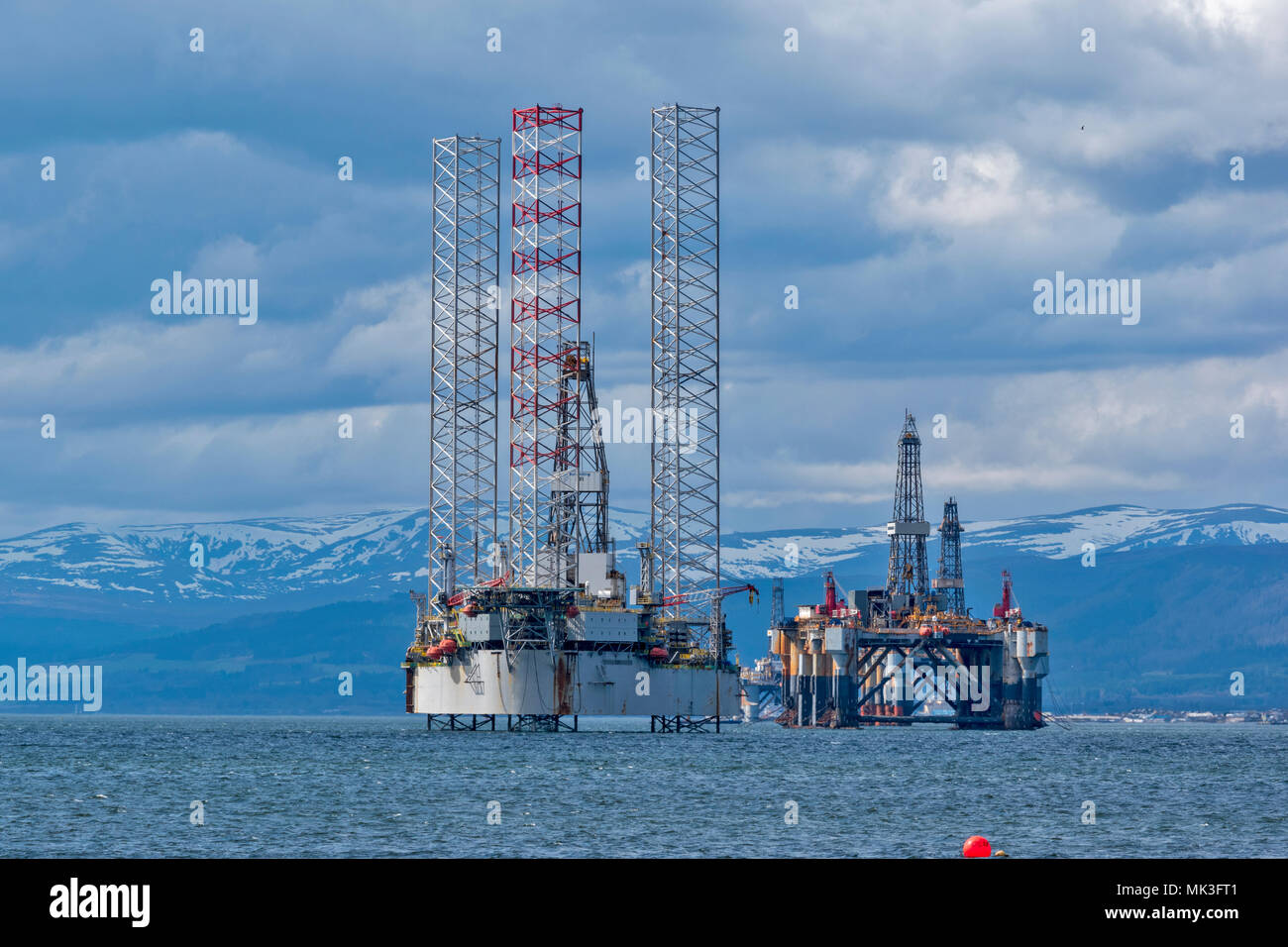 CROMARTY FIRTH SCOTLAND BAUG OIL DRILLING PLATFORM AND TOWERS WITH  DECOMMISSIONED OR REPAIRED OIL RIG LYING OFF CROMARTY VILLAGE Stock Photo