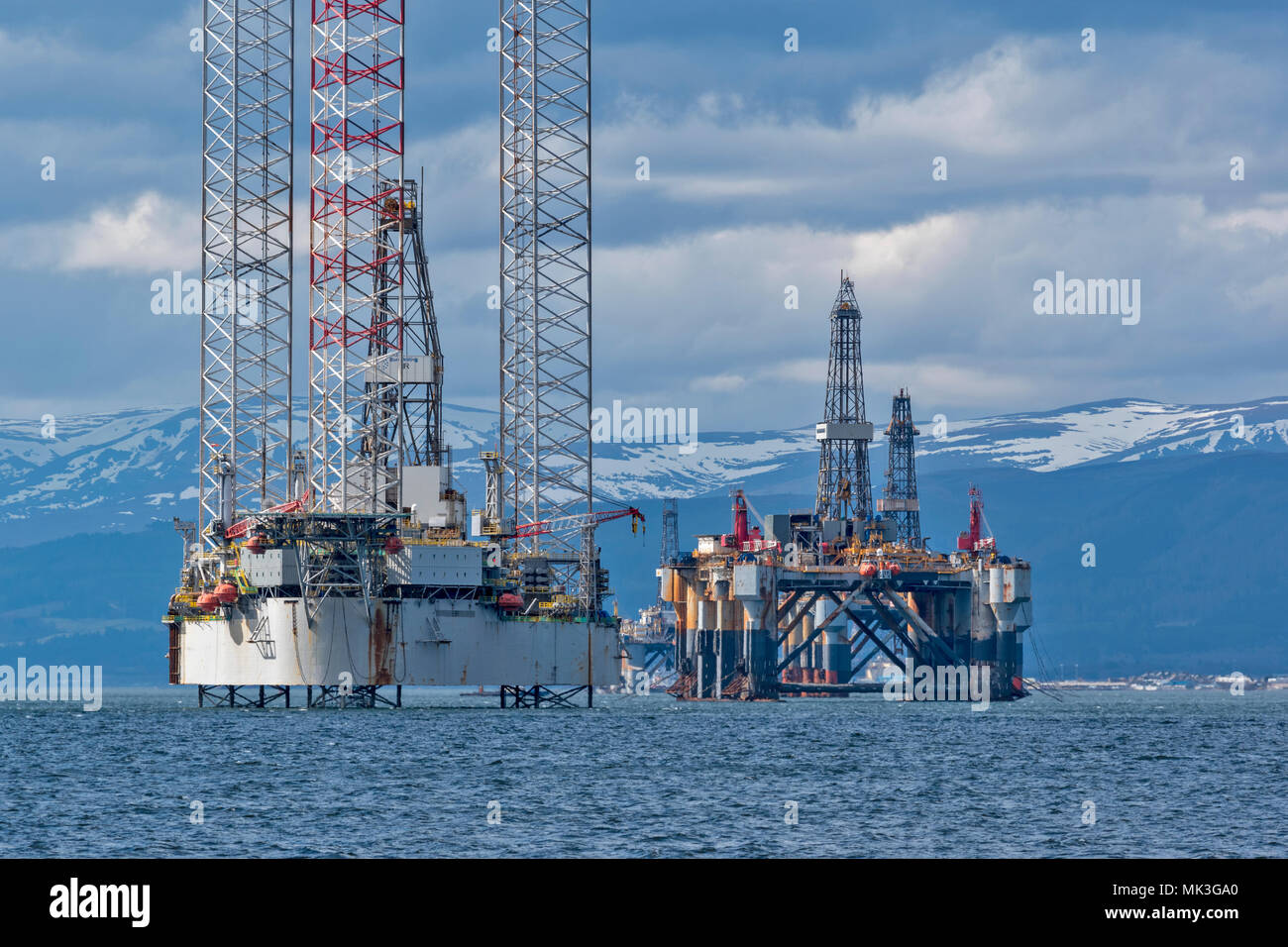 CROMARTY FIRTH SCOTLAND TALL OIL RIG OR DRILLING PLATFORM BAUG WITH DECOMMISSIONED OIL RIG AND SNOW COVERED HILLS Stock Photo