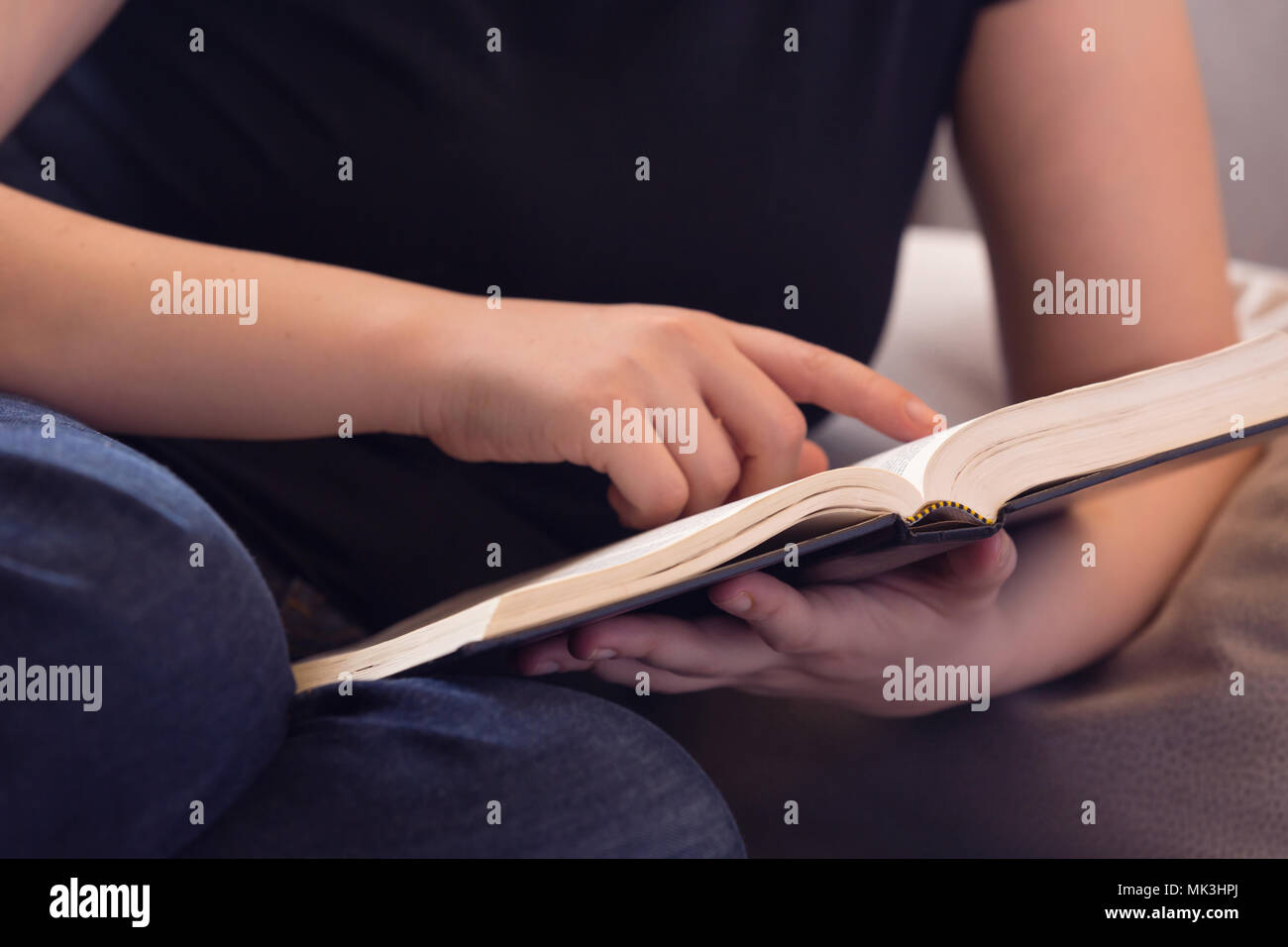 Young woman relaxing on the couch reading the Bible Stock Photo