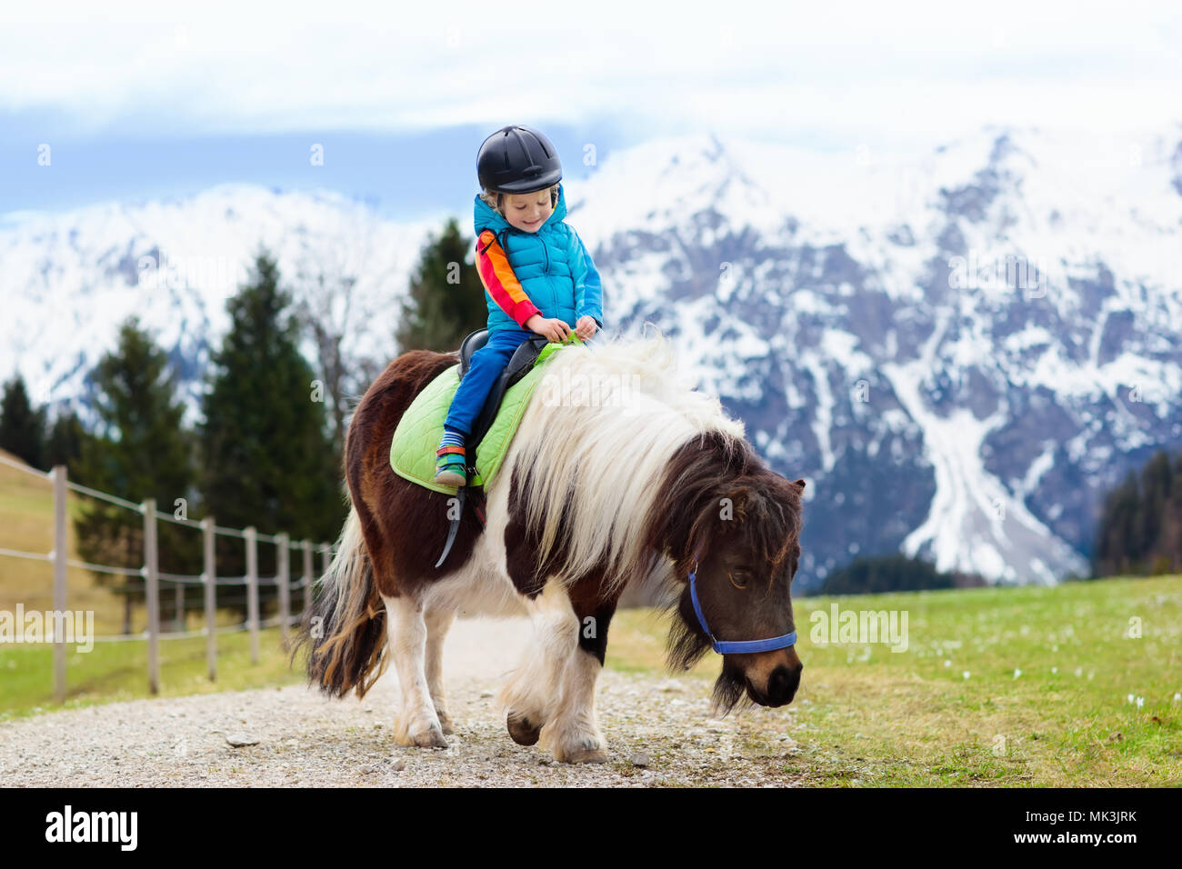 Kids riding pony in the Alps mountains. Family spring vacation on horse ...