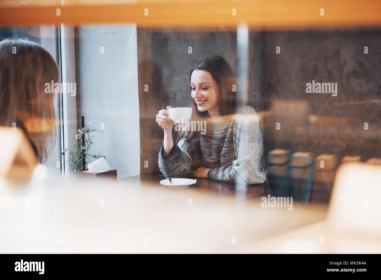 Two friends enjoying coffee together in a coffee shop as they sit at a