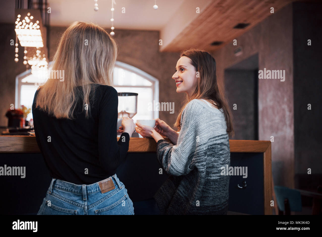 Two friends enjoying coffee together in a coffee shop as they sit at a