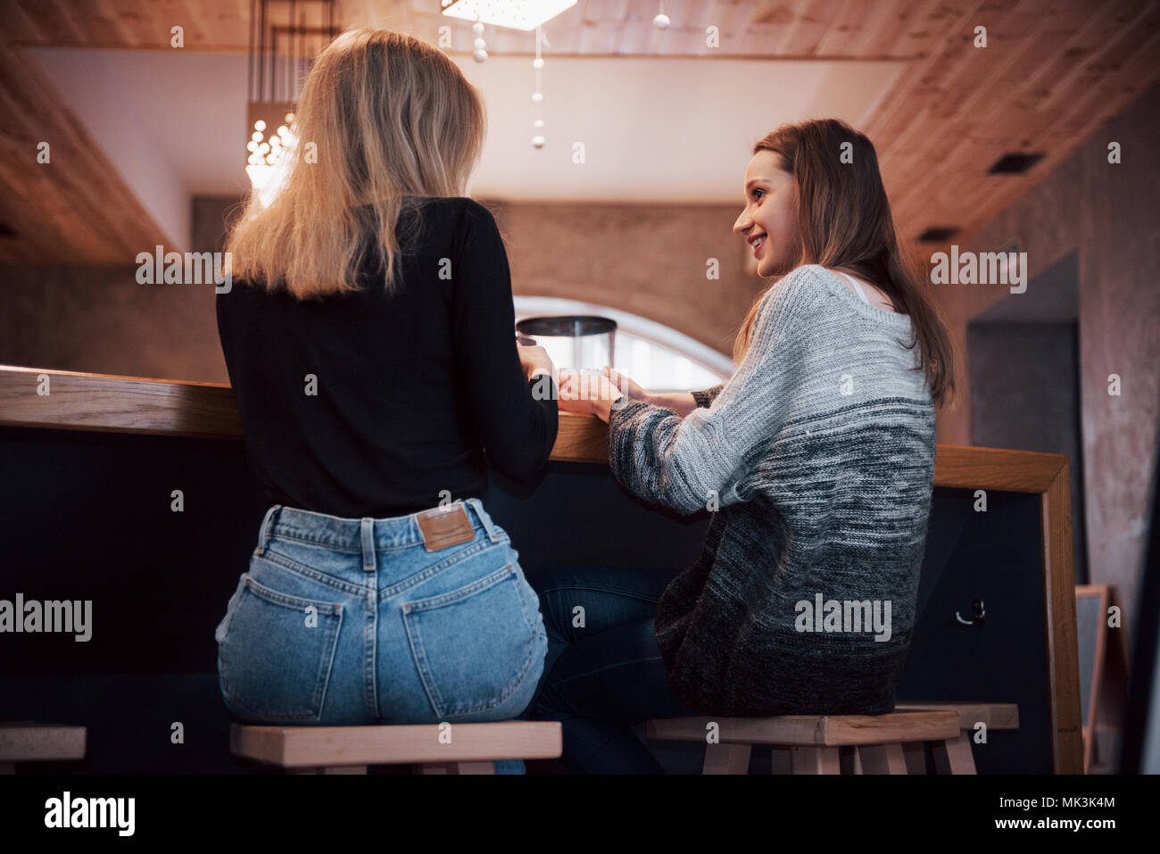 Two friends enjoying coffee together in a coffee shop as they sit at a table chatting Stock Photo