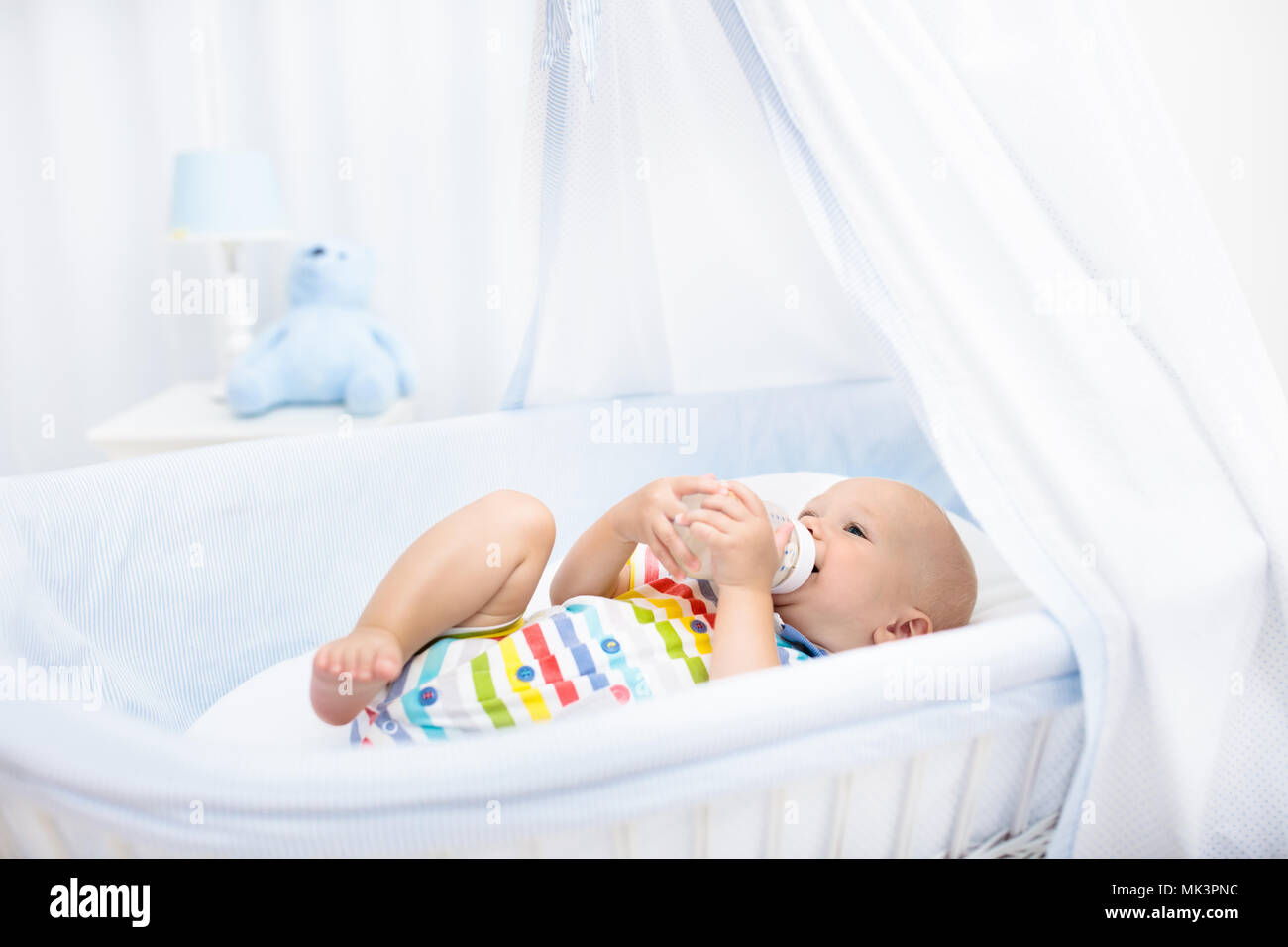 Baby Drinking Milk In White Crib Infant Boy With Formula Bottle