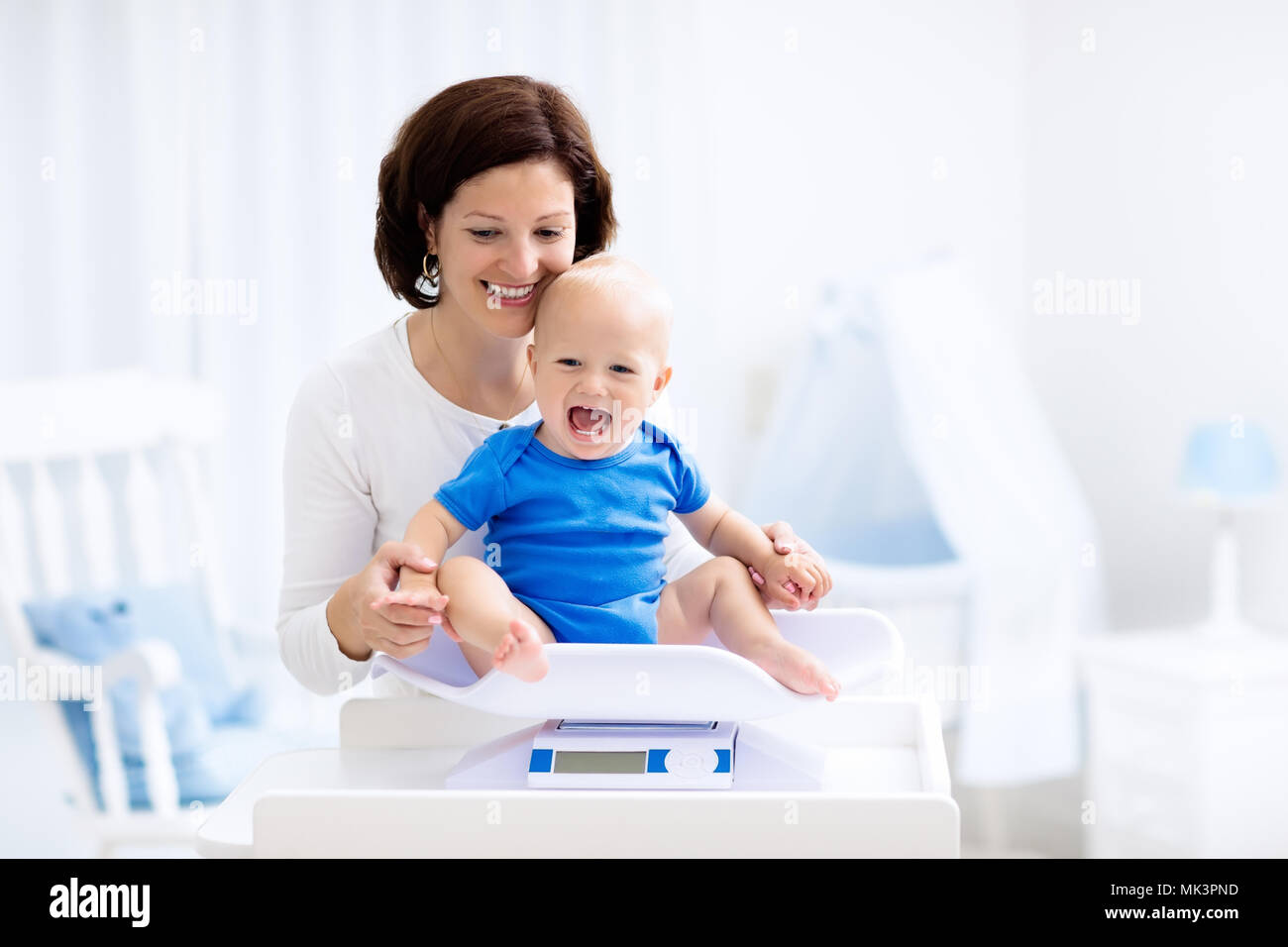 Mother and baby in diaper on changing table. Mom changing nappy on baby boy. Kids nursery