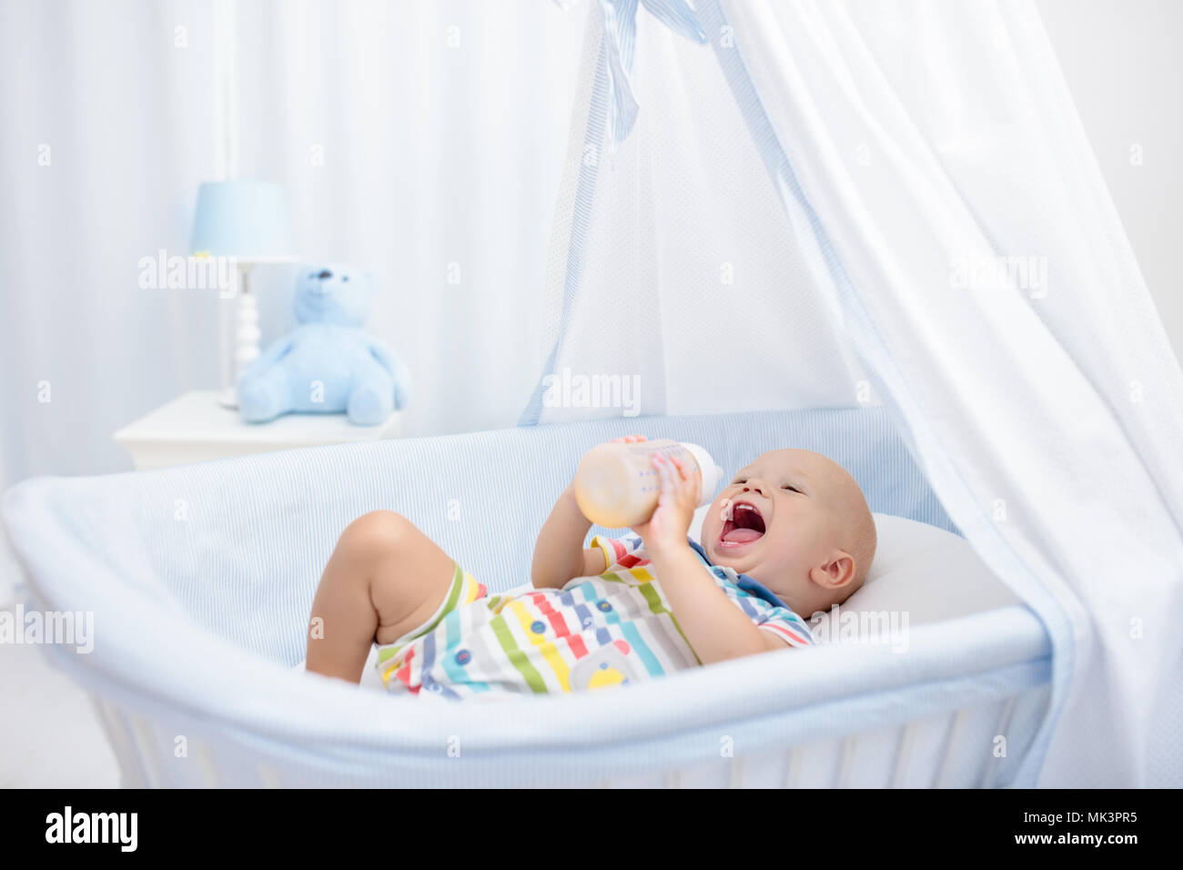 Baby Drinking Milk In White Crib Infant Boy With Formula Bottle