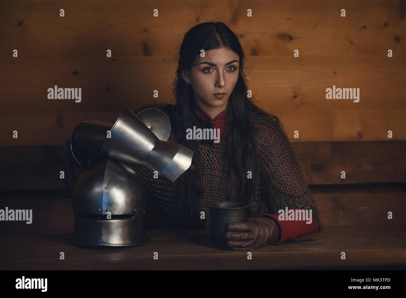Portrait of beautiful medieval girl warrior in a chainmail hood with helmet in hands Stock Photo