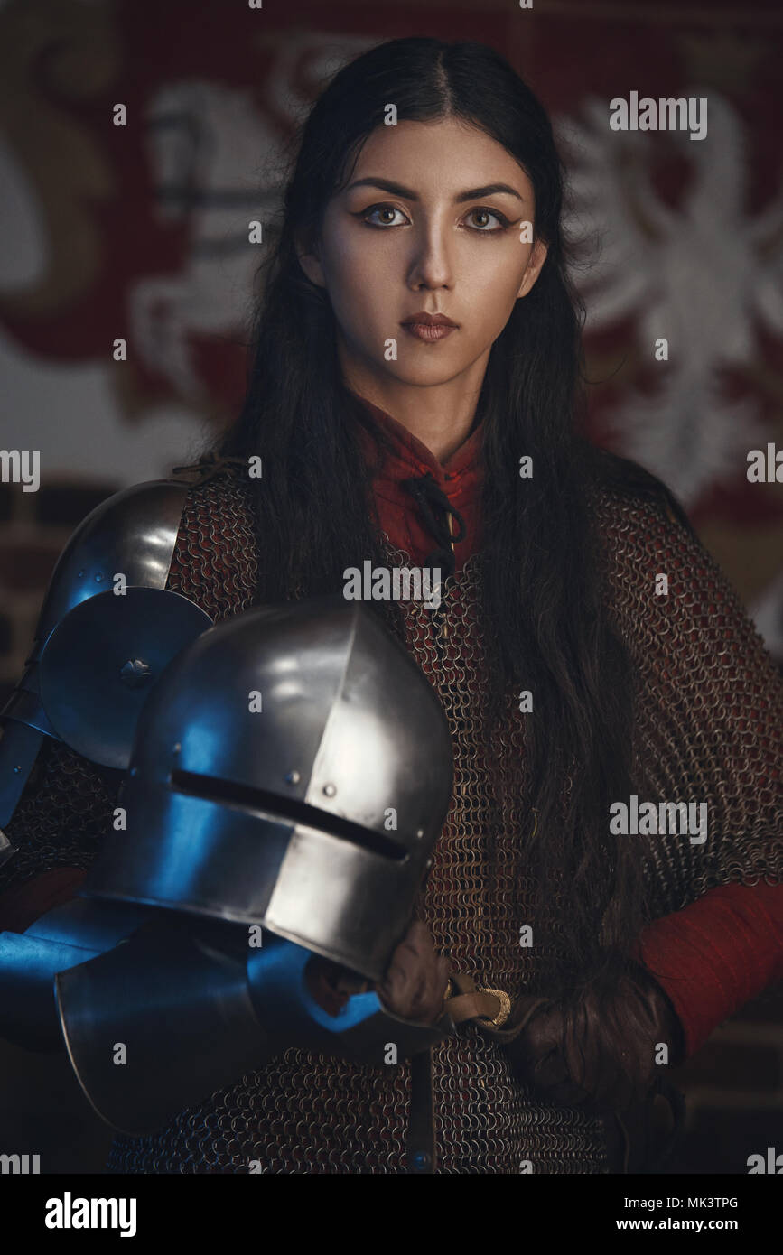 Portrait of beautiful medieval girl warrior in a chainmail hood with helmet in hands Stock Photo