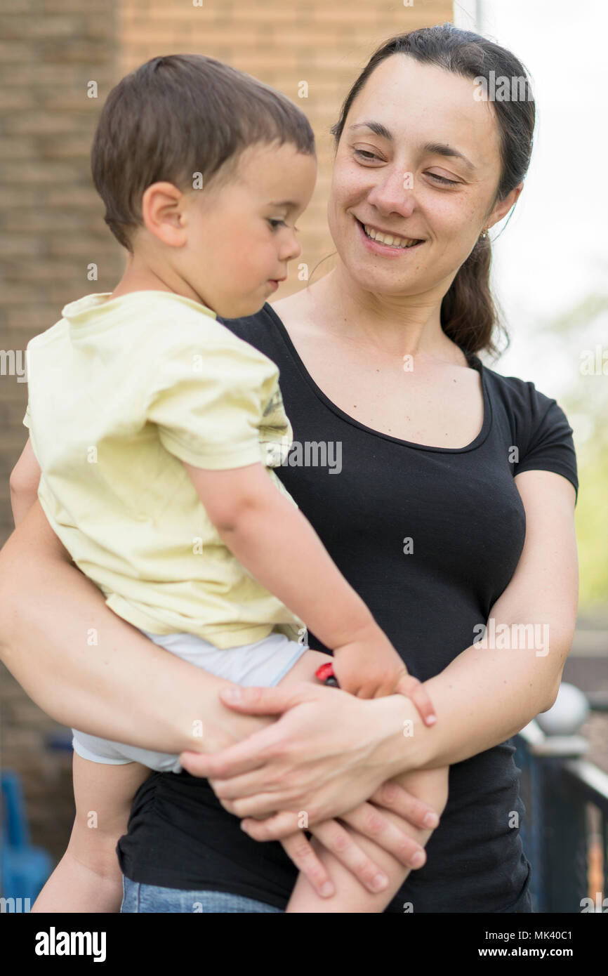 A woman is holding a baby in her arms. baby in the arms of mother. Stock Photo