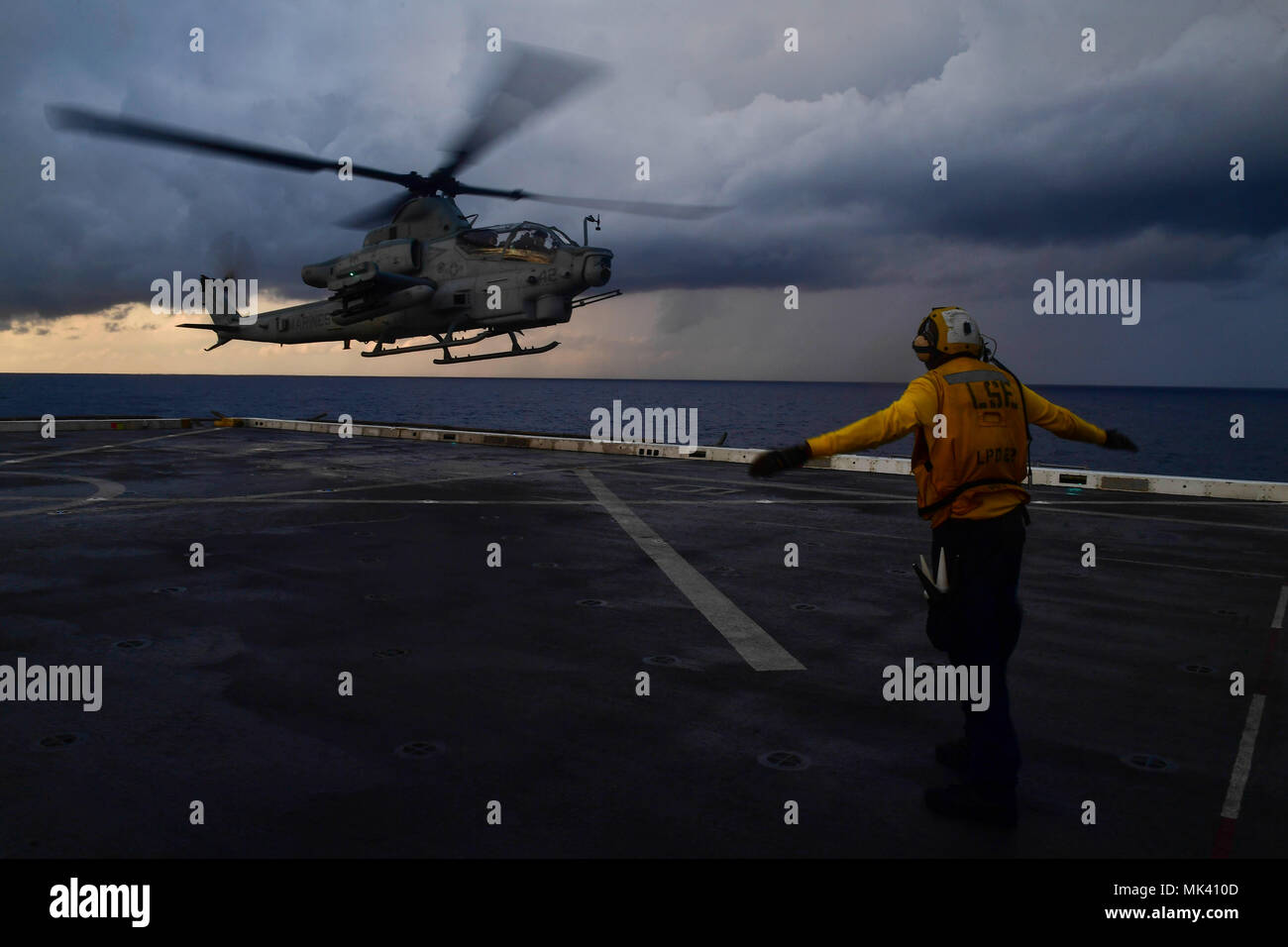 U.S. Navy Aviation Boatswain’s Mate (Handling) Airman Anthony Similton, from Augusta, Georgia, directs a Marine Corps AH-1Z Viper attack helicopter, attached to Marine Medium Tiltrotor Squadron (VMM) 161 (Reinforced), on the flight deck of the amphibious transport dock ship USS San Diego (LPD 22) in the Mediterranean Sea Nov. 1, 2017. The San Diego is deployed with the America Amphibious Ready Group and the 15th Marine Expeditionary Unit to support maritime security and theater security cooperation in efforts in the U.S. 6th Fleet area of operations. (U.S. Navy photo by Mass Communication Spec Stock Photo
