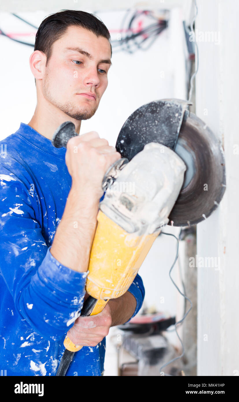 Construction worker cutting concrete wall by using handheld circular saw Stock Photo