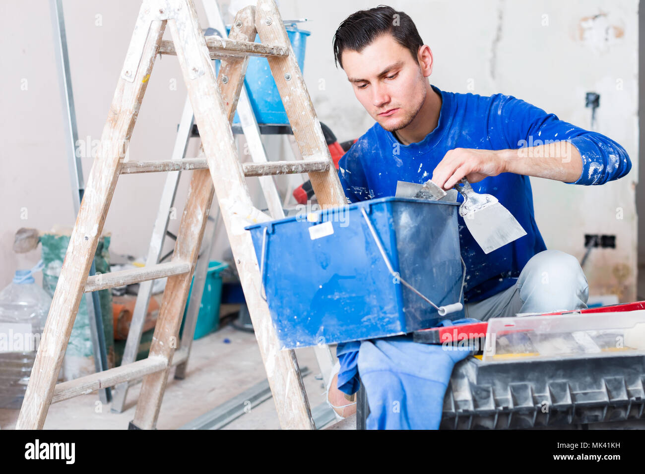 Young builder handyman choosing necessary tool in toolbox Stock Photo