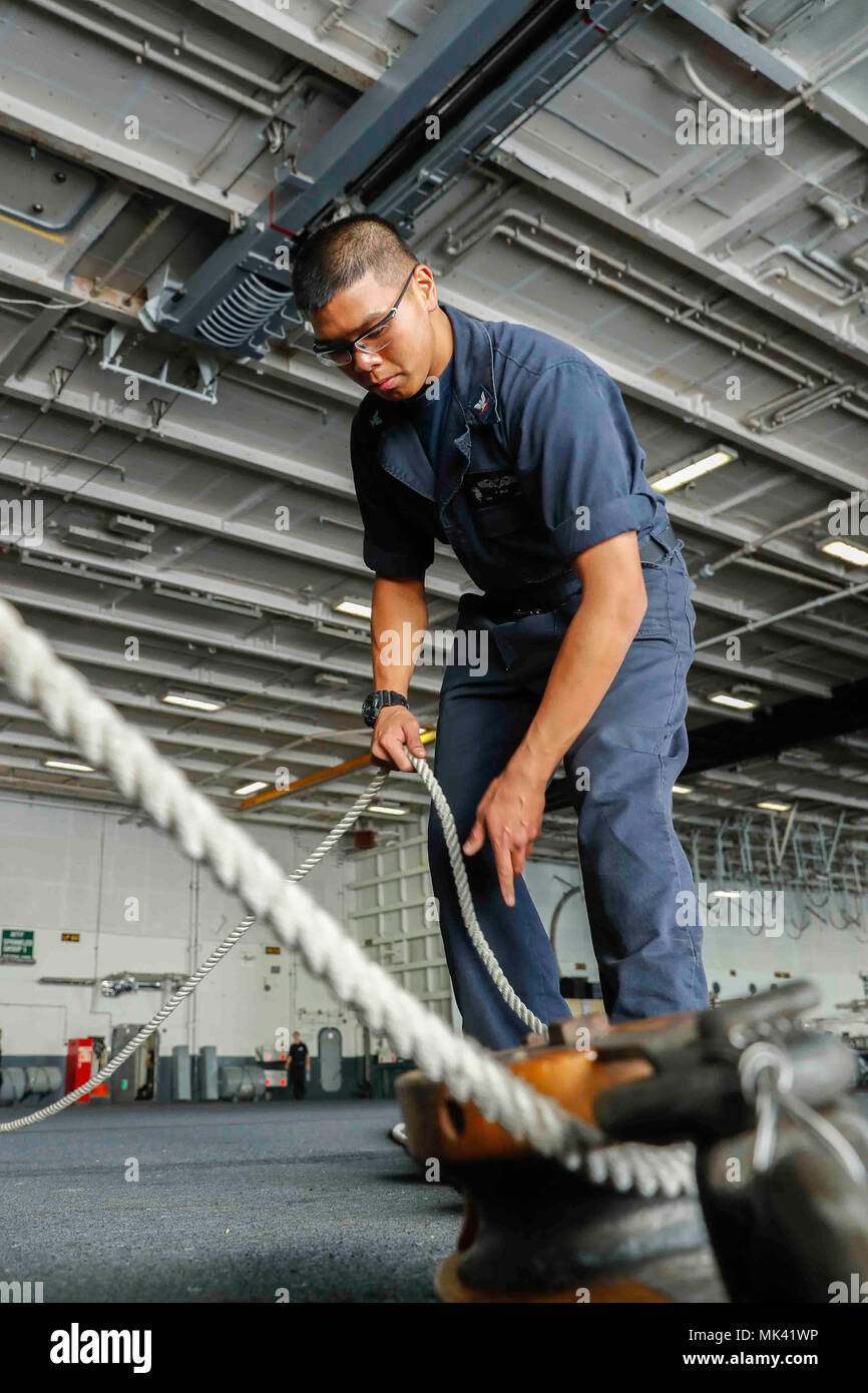 171101-N-EN275-134 ATLANTIC OCEAN (Nov. 1, 2017) Boatswain's Mate 3rd Class Addison Mila fakes out line in preparation for an underway replenishment in the hangar bay aboard the Nimitz-class aircraft carrier USS Abraham Lincoln (CVN 72). Abraham Lincoln is underway conducting carrier qualifications and training. (U.S. Navy photo by Mass Communication Specialist 3rd Class Jacob Smith/Released) Stock Photo