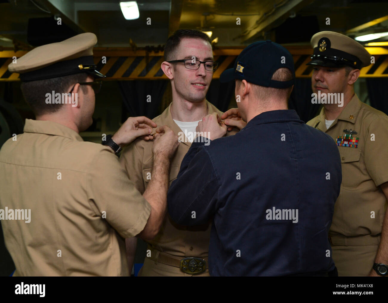 INDIAN OCEAN (Nov. 1, 2017) U.S. Navy Chief Machinist's Mate (Nuclear) Kenneth Kuper, from Laurel, Mont., has his collar devices removed prior to being commissioned to the rank of ensign aboard the aircraft carrier USS Nimitz (CVN 68), Nov. 1, 2017, in the Indian Ocean. The Nimitz Carrier Strike Group is on a regularly scheduled deployment in the 7th Fleet area of responsibility in support of maritime security operations and theater security cooperation efforts. (U.S. Navy photo by Mass Communication Specialist 3rd Class Cole Schroeder) Stock Photo