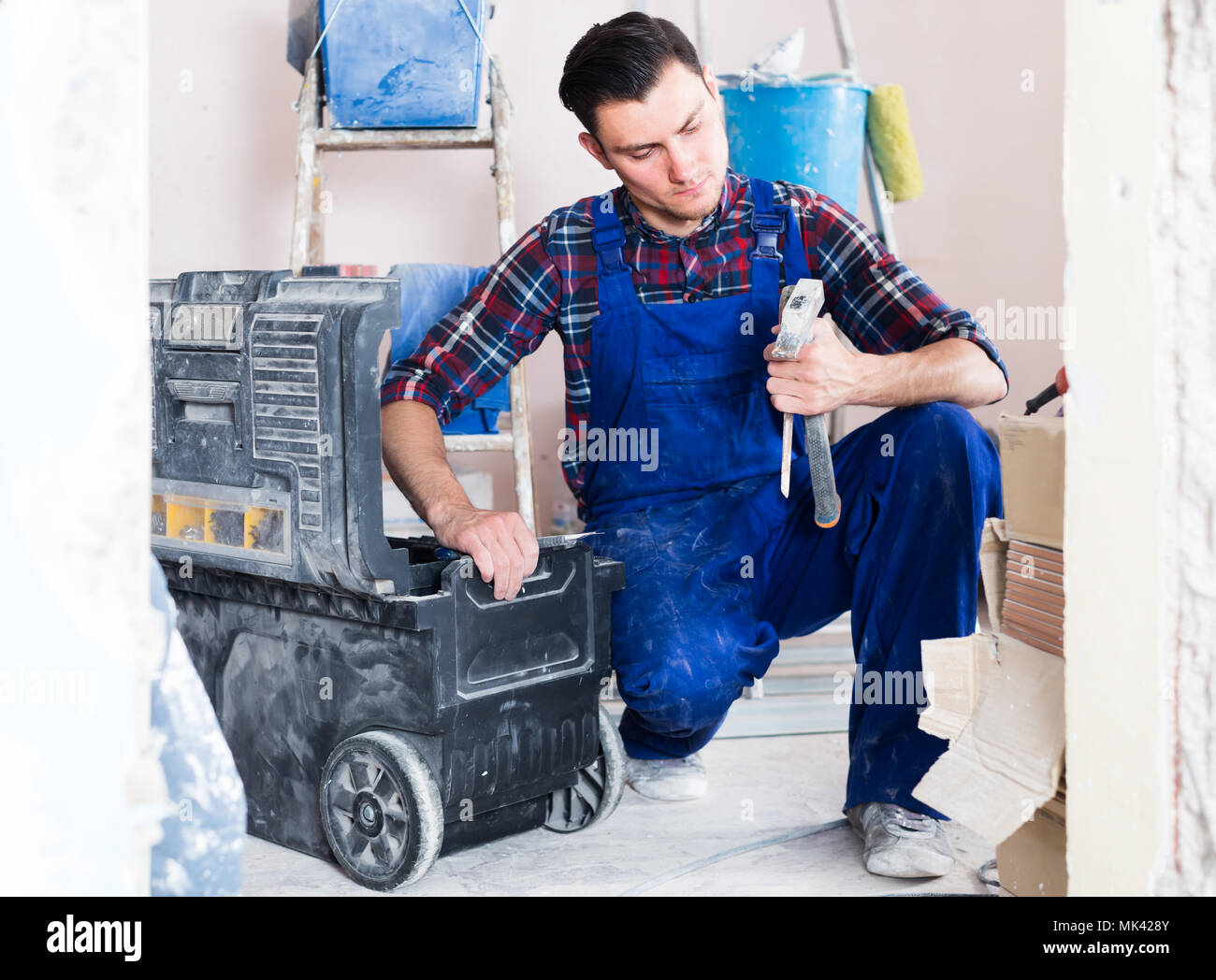 attentive builder handyman choosing necessary tool in toolbox Stock Photo