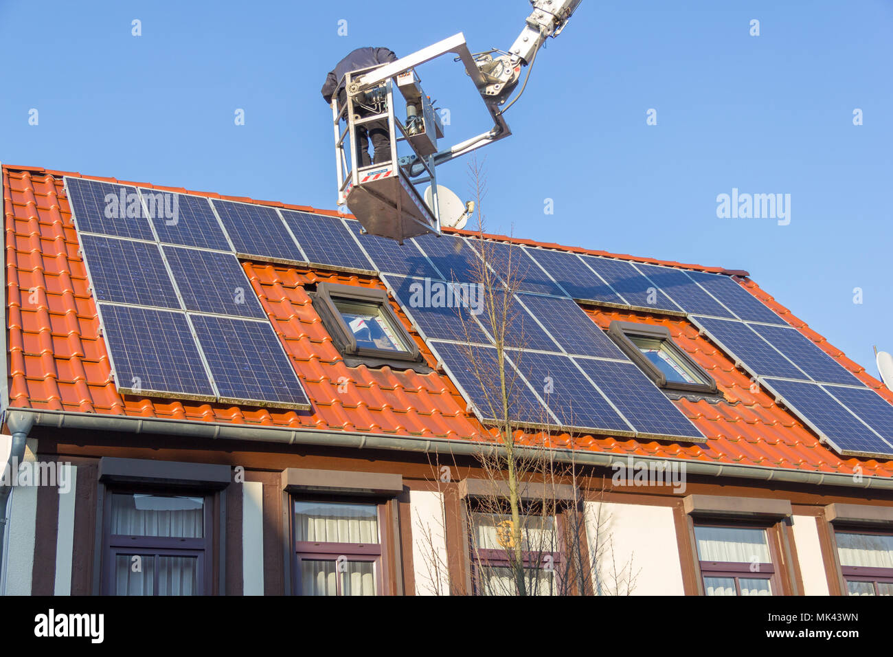 A german worker is mounting a photovoltaic system on a roof Stock Photo