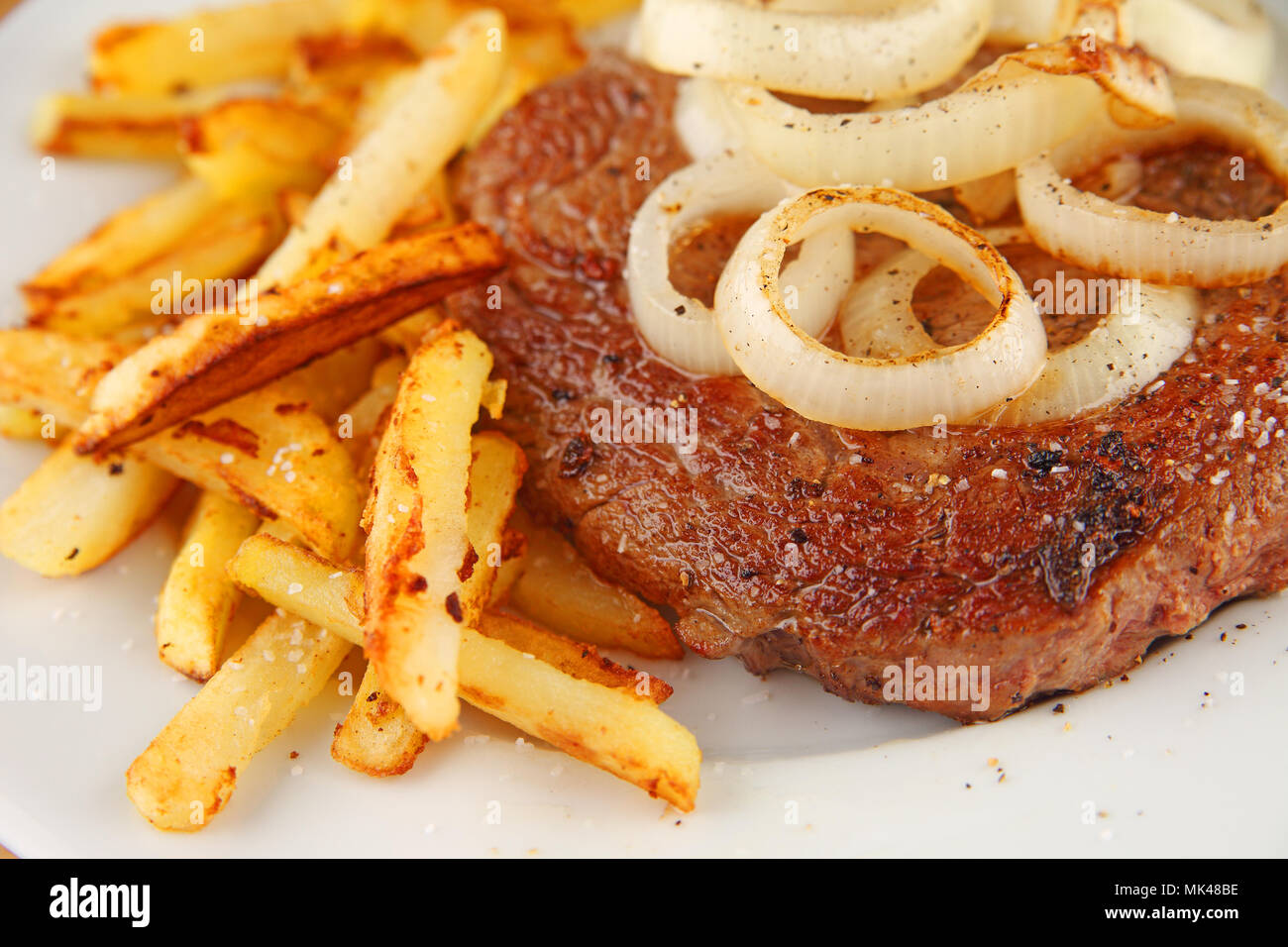 Steak with sauteed onions and french fries Stock Photo Alamy