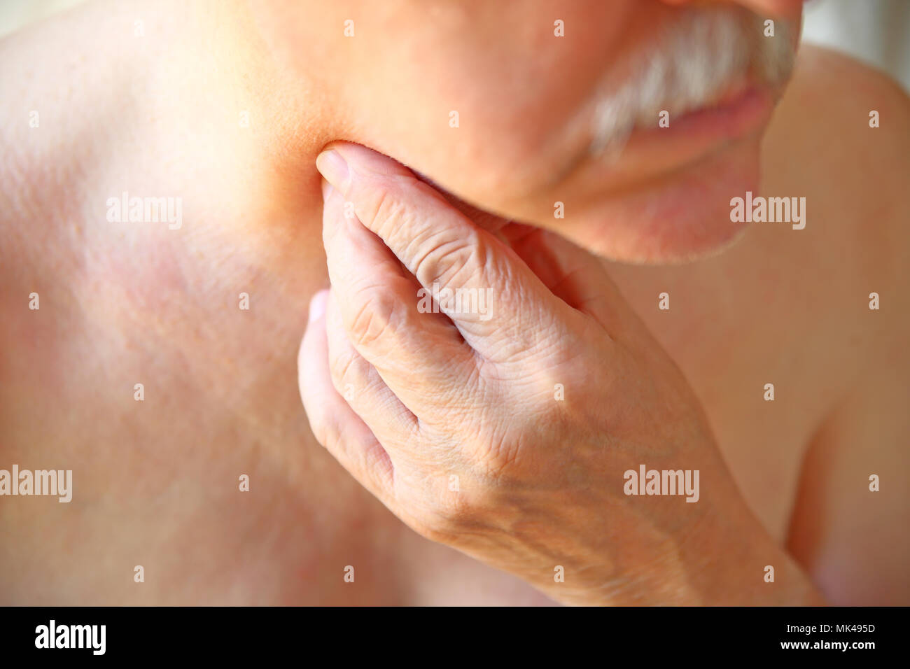 An older man touches his painful throat with his fingers Stock Photo