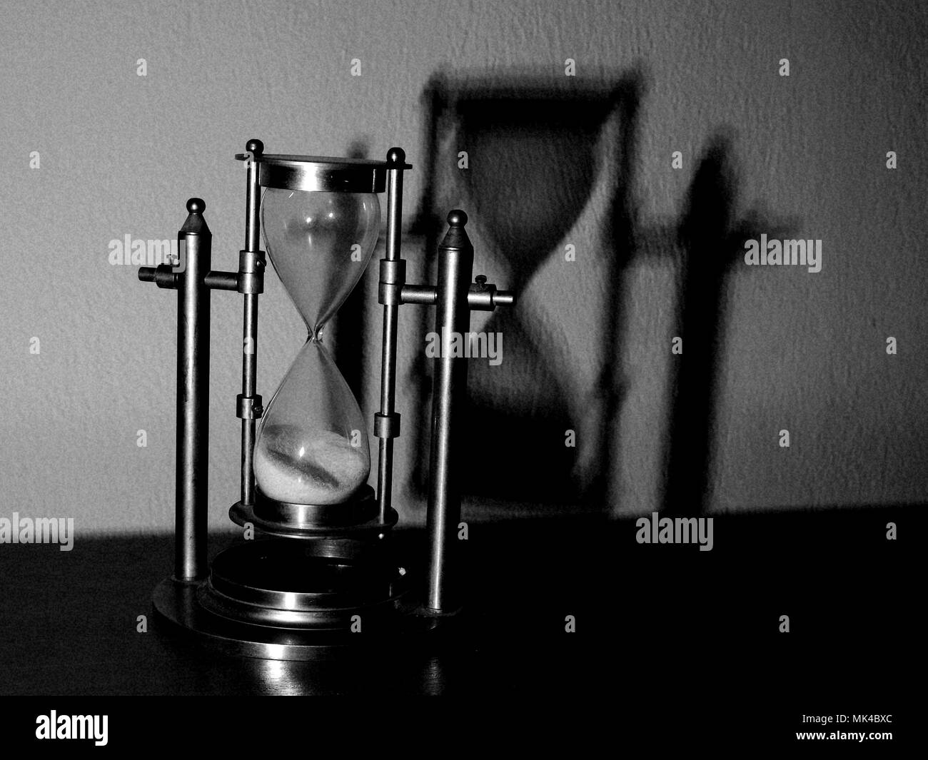 Hourglass casting shadow on white wall. Concept: time. Stock Photo