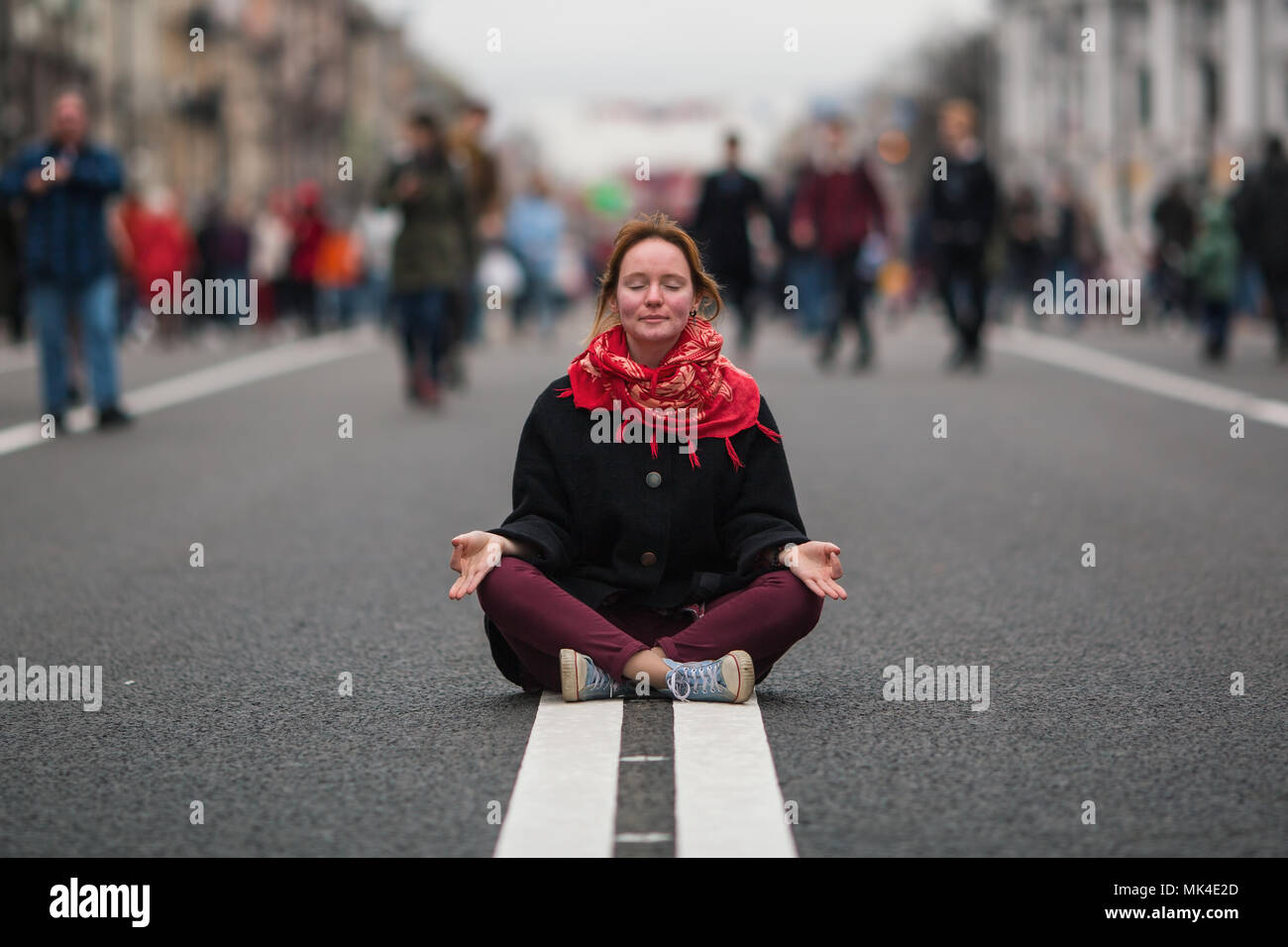 Cute girl sitting in meditation in the middle of a busy street in the ...