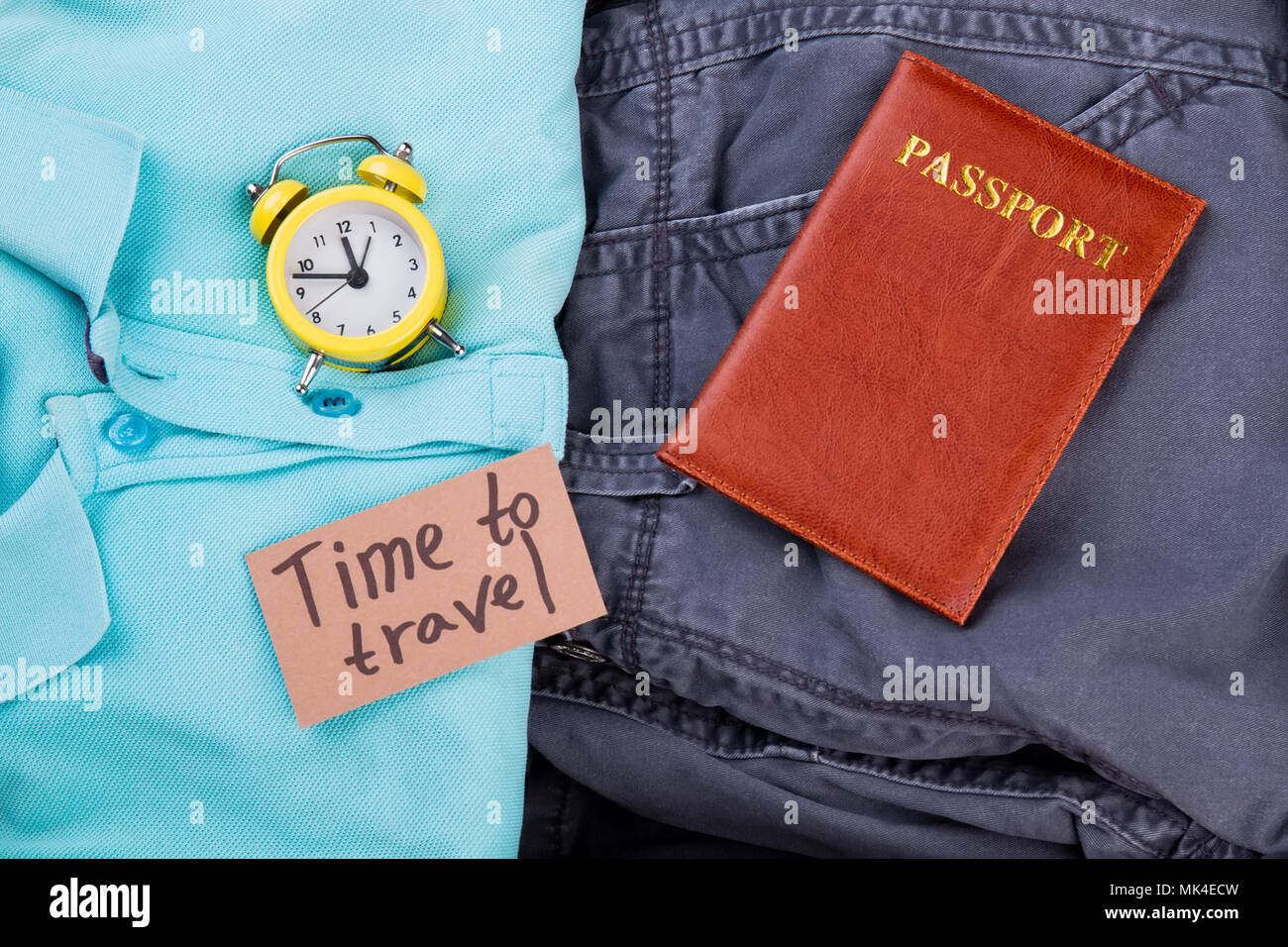 Flat lay time to travel concept. Male clothes, alarm clock and passport. Close up, top view. Stock Photo
