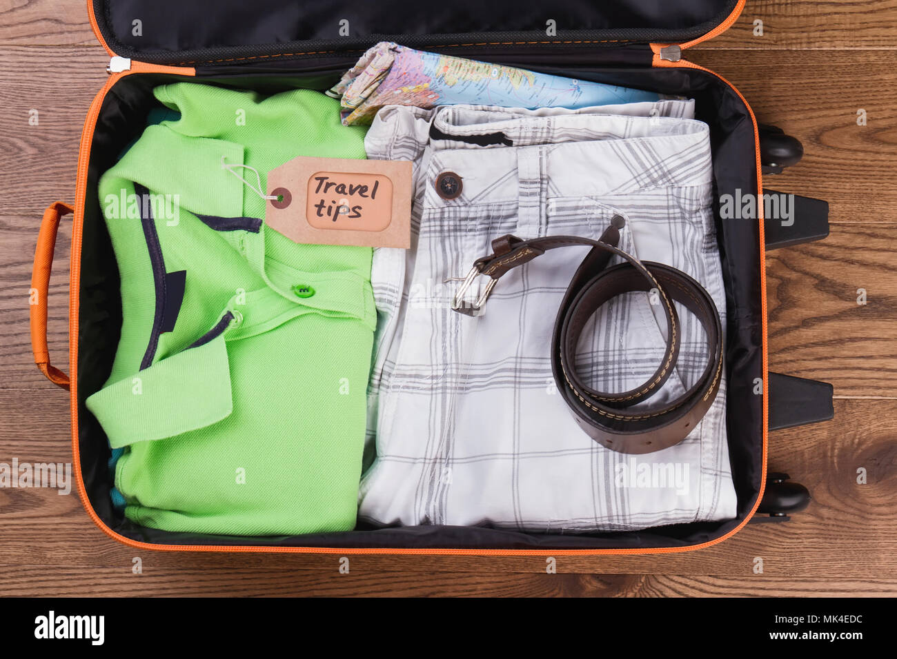Folded summer apparel and belt. Travel tips, flat lay. Male clothes in suitcase. Stock Photo
