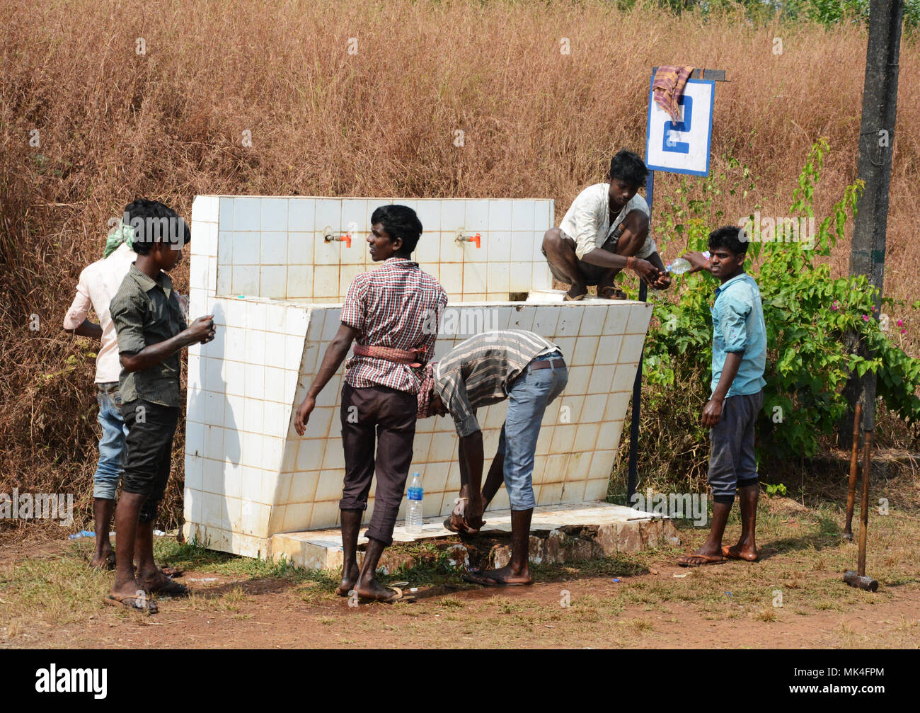 A group of railway workers cooling off at a washing station beside the tracks, India Stock Photo