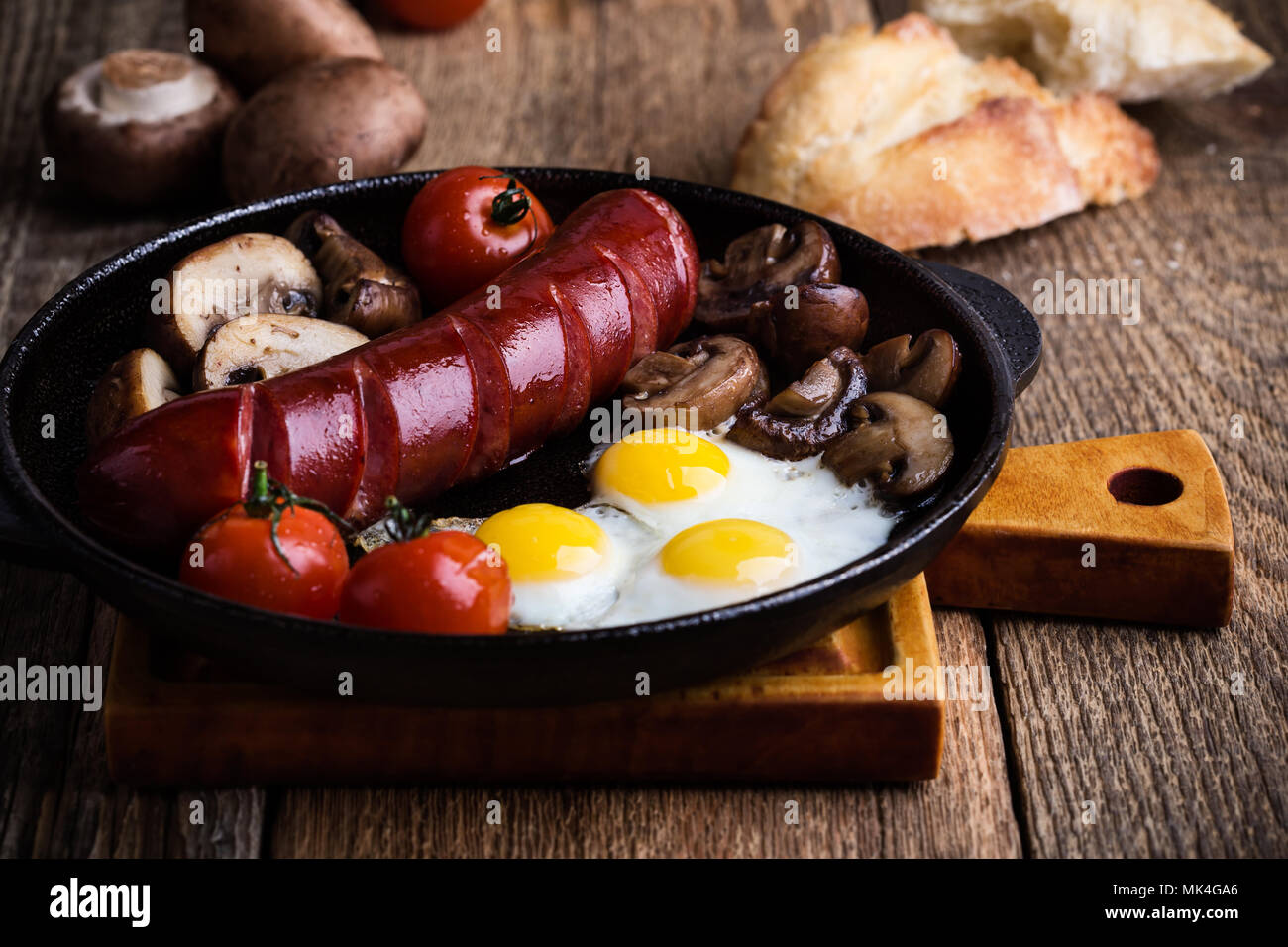 Fried quail eggs, sausage, tomatoes and mushrooms on cast iron skillet