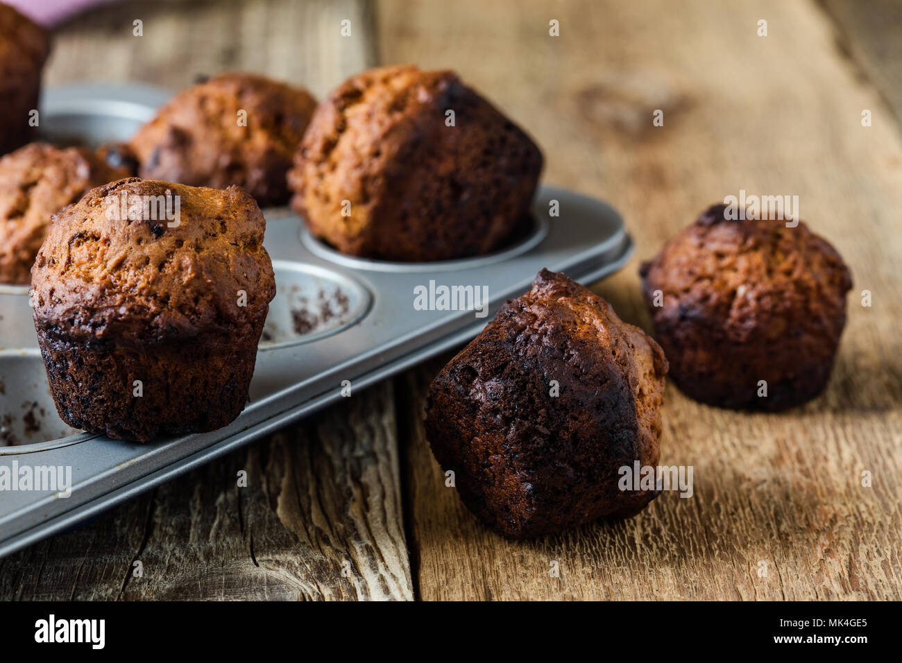 Burnt muffins in baking pan on rustic wooden table, messy kitchen situation in the kitchen Stock Photo