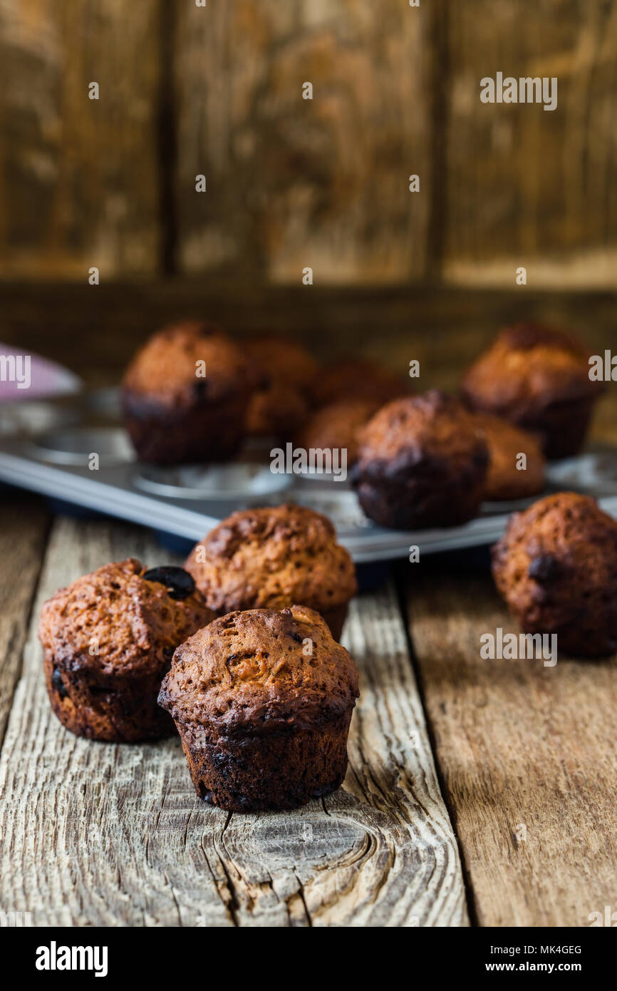 Burnt muffins in baking pan on rustic wooden table, messy kitchen situation in the kitchen Stock Photo