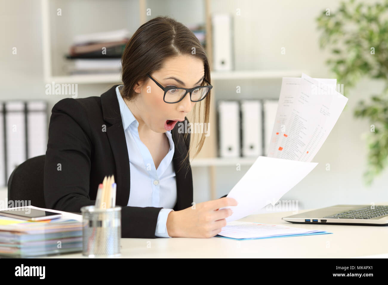 Amazed executive checking sales results in several documents at office Stock Photo