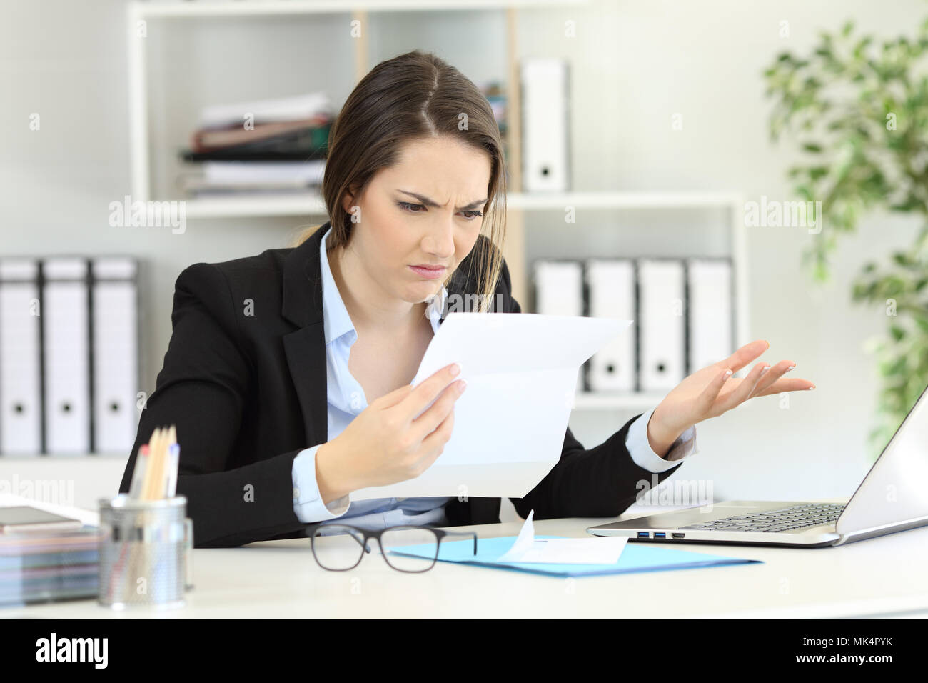 Confused office worker reading documents on a desktop Stock Photo