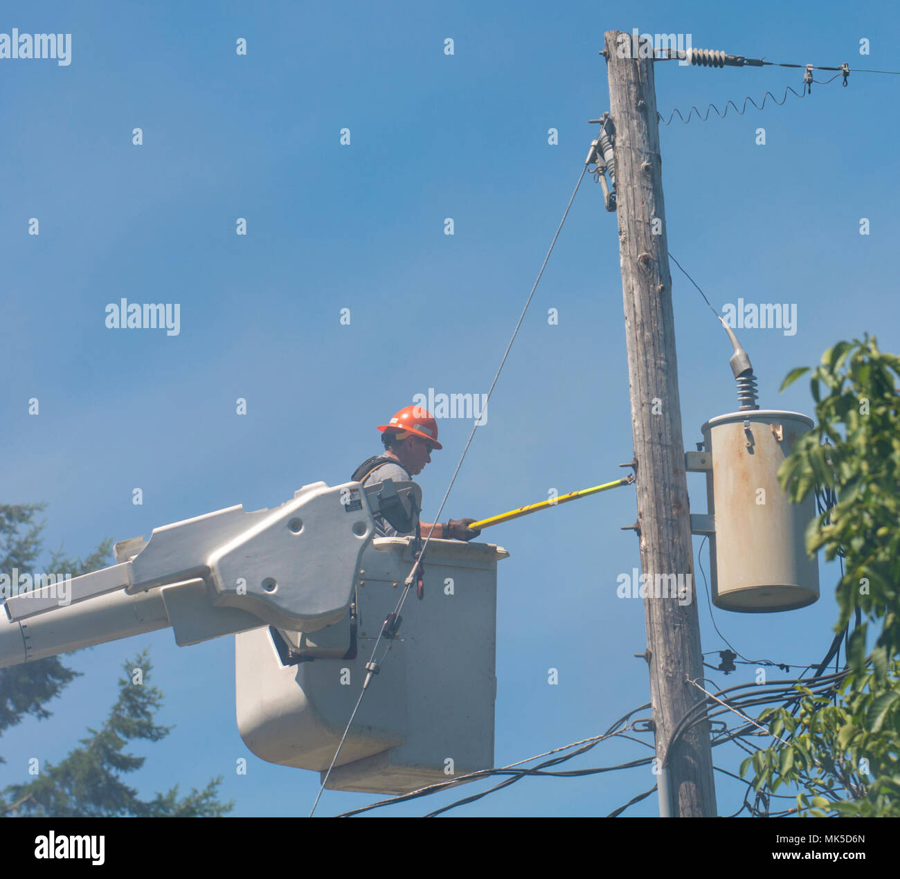 A line man stands on a truck ladder in the smoke and disconnects power ...
