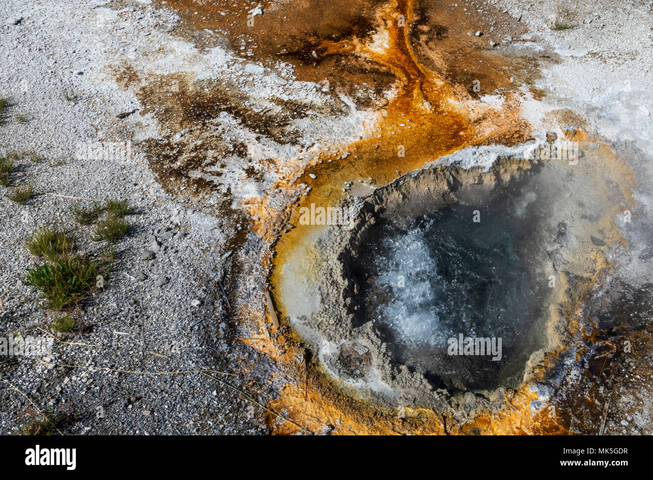 Closeup of bubbling Hot spring surrounded by rusty water and white dirt. Stock Photo