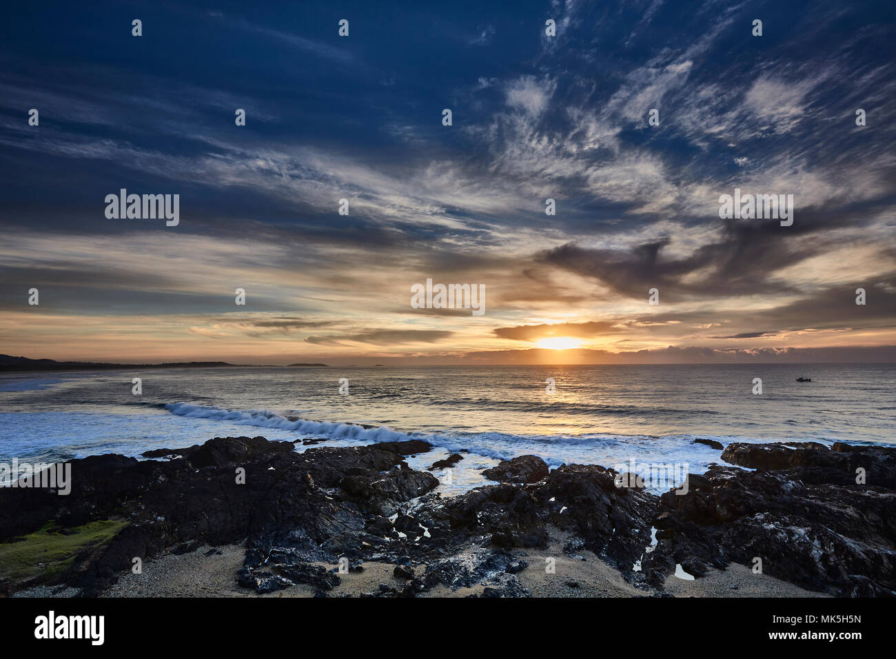 An impressive sunrise at Boambee Headland in autumn with the sun just breaking through the clouds, Coffs Harbour, New South Wales, Australia Stock Photo