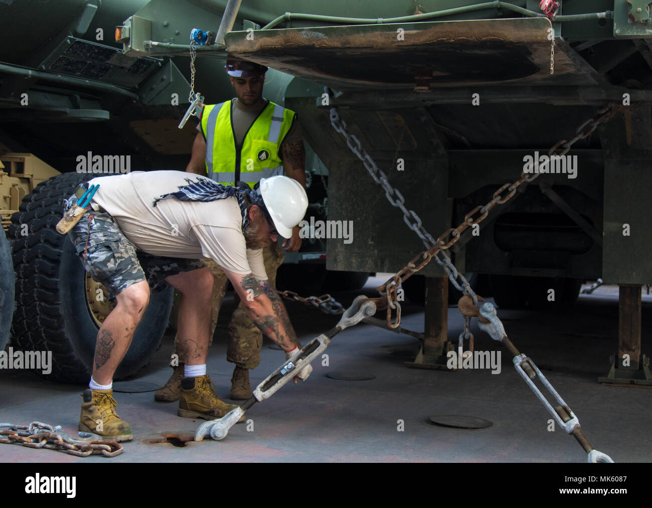 PORT OF SHUAIBA, Kuwait (Nov 1, 2017) - A civilian contractor and a soldier with the 840th Transportation Battalion loosens the supports on equipment stored on the weather deck of the USNS Bob Hope. USNS Bob Hope was carrying vehicles, large mechanical equipment, and other motorized tools to be used in the Central Command Area of Responsibility. (U.S. Army photo by Sgt. Jaccob Hearn) Stock Photo