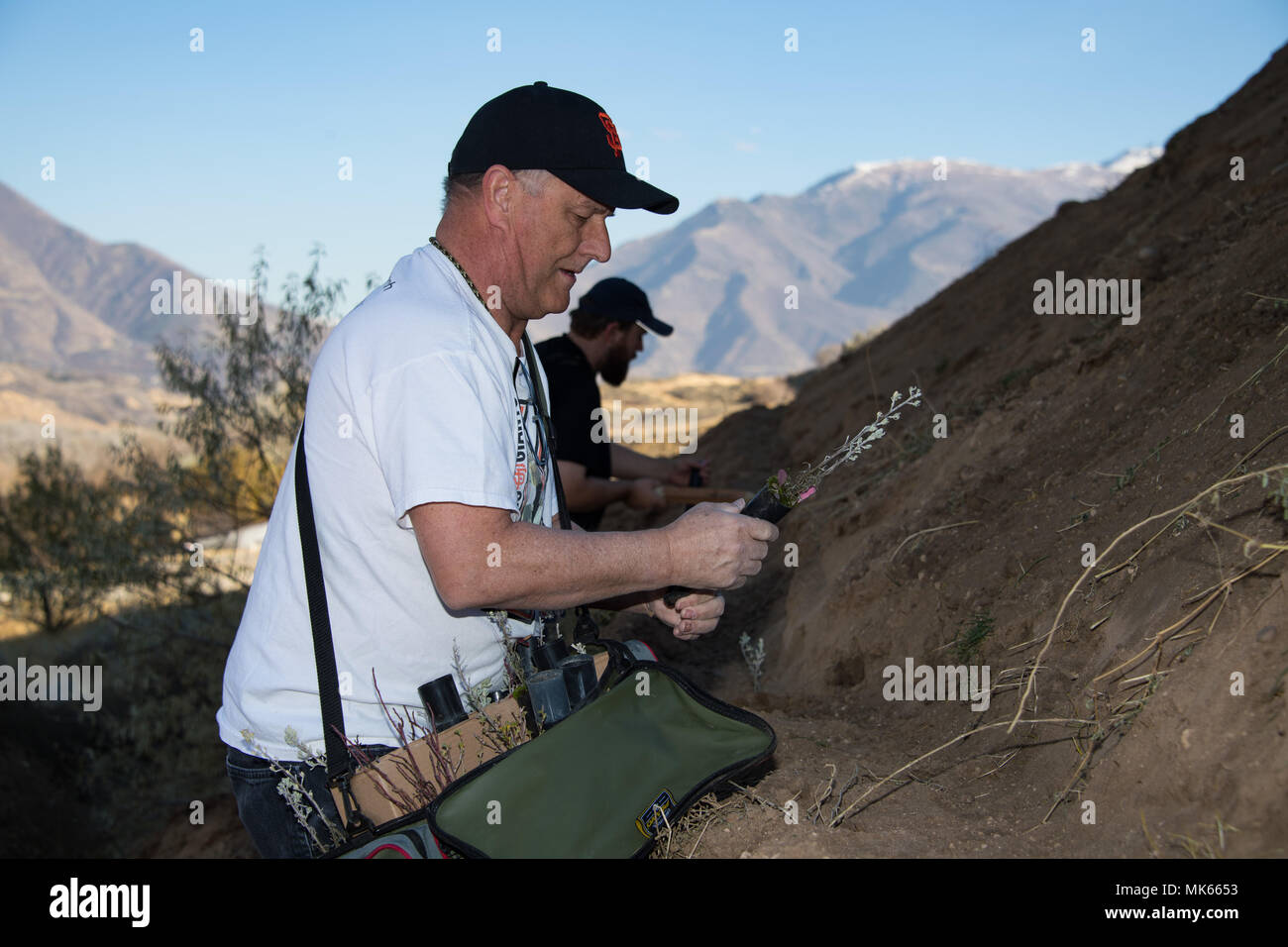 Volunteer Jimmy Snyder, an environmental specialist assigned to the 75th Civil Engineering Group, prepares to plant a sage brush seedling, Hill Air Force Base, Utah, Nov. 9, 2017. Volunteers planted gamble oak, serviceberry, sagebrush, bitterbrush, cliffrose and wild rose on a former landfill site as part of a land enhancement project. (U.S. Air Force photo by R. Nial Bradshaw) Stock Photo