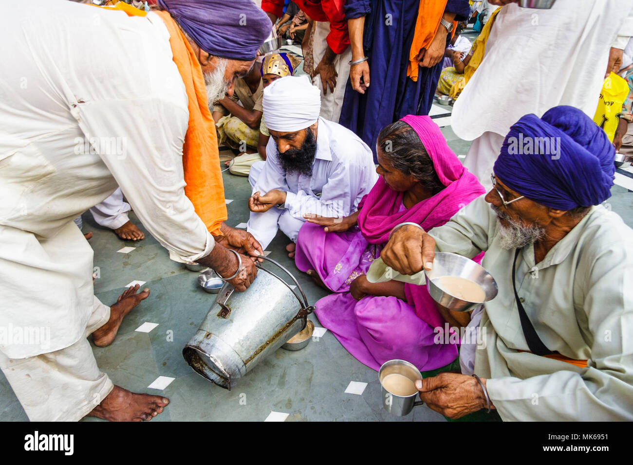 Amritsar, Punjab, India :  A Sikh man offers free tea to the pilgrims at the Guru Ka Langar community kitchen of the Golden Temple where free food for Stock Photo