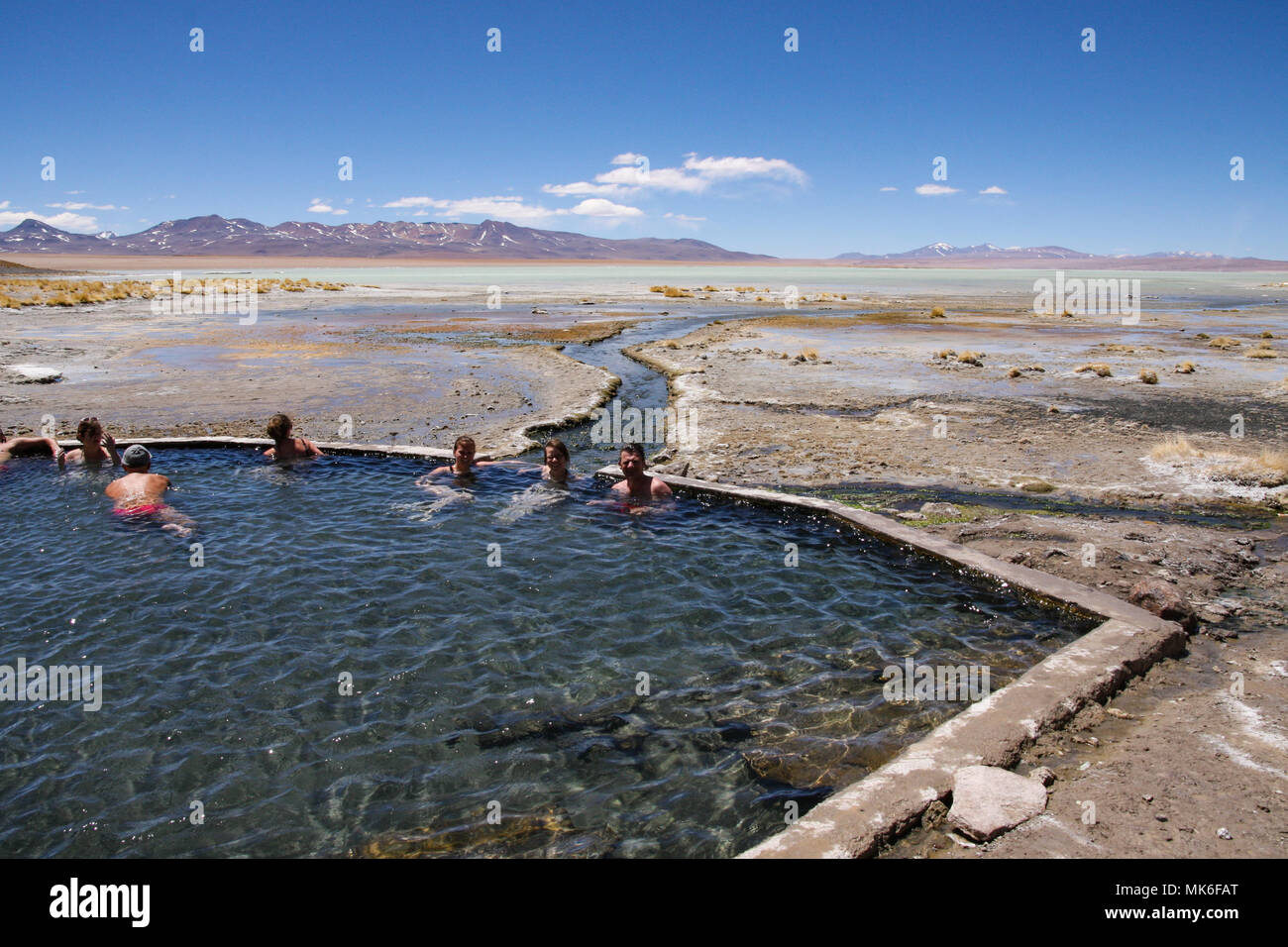 TUPIZA, BOLIVIA - SEPTEMBER 23, 2011: A group of people relax in the hot springs of Salar de Uyuni while enjoying the stunning desert scenery Stock Photo