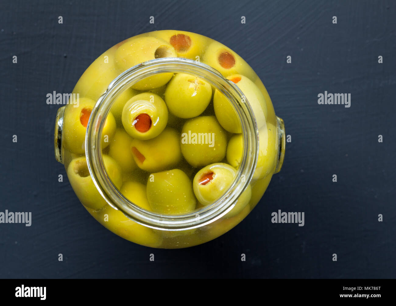 Jar of stuffed green olives in brine close up top view photo with copy space for text Stock